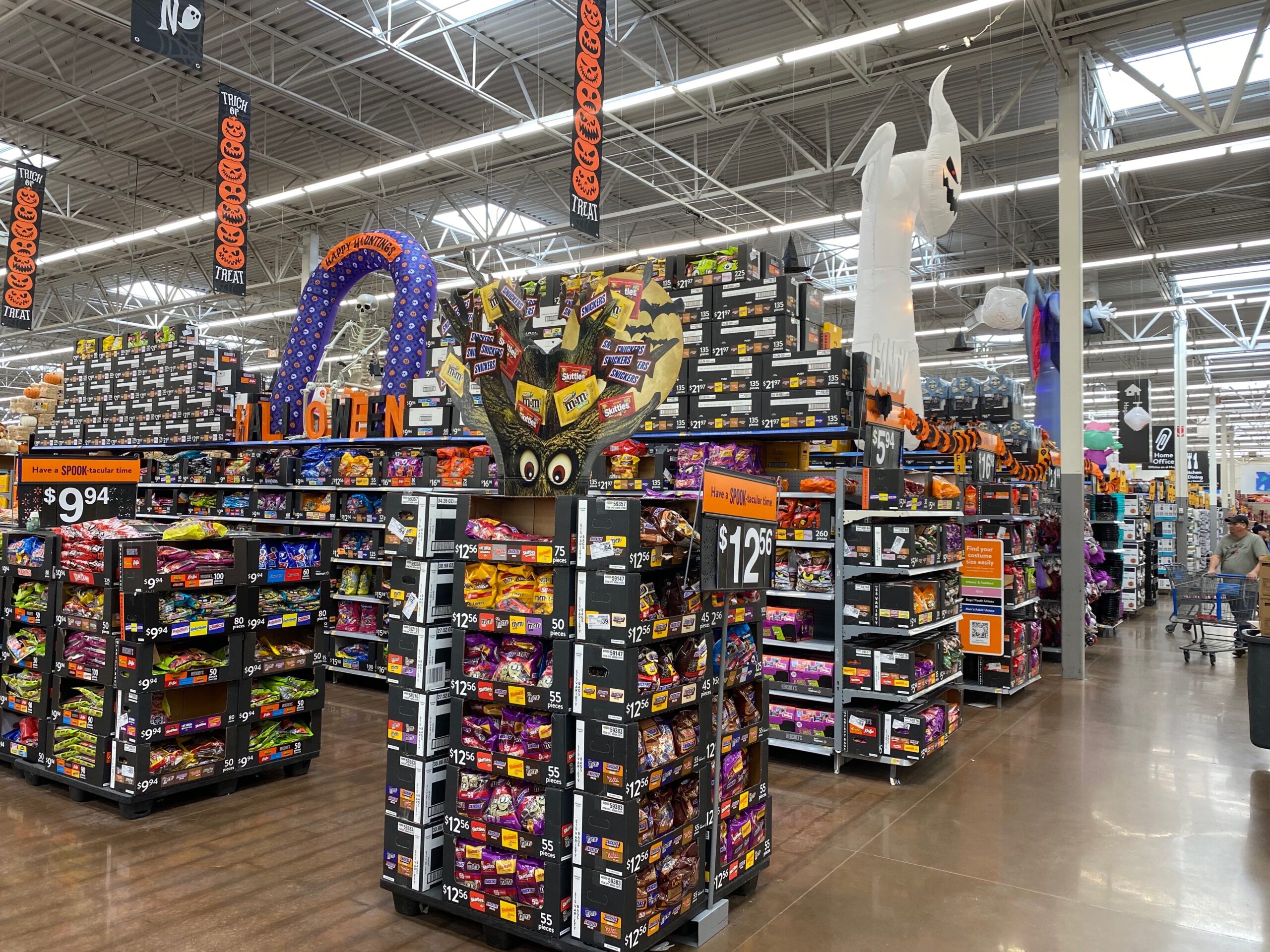 Interior of Walmart Supercenter Beaumont California during Halloween season, featuring large Halloween decorations, candy displays, inflatable ghosts, themed signage, and wide aisles under a high industrial ceiling.