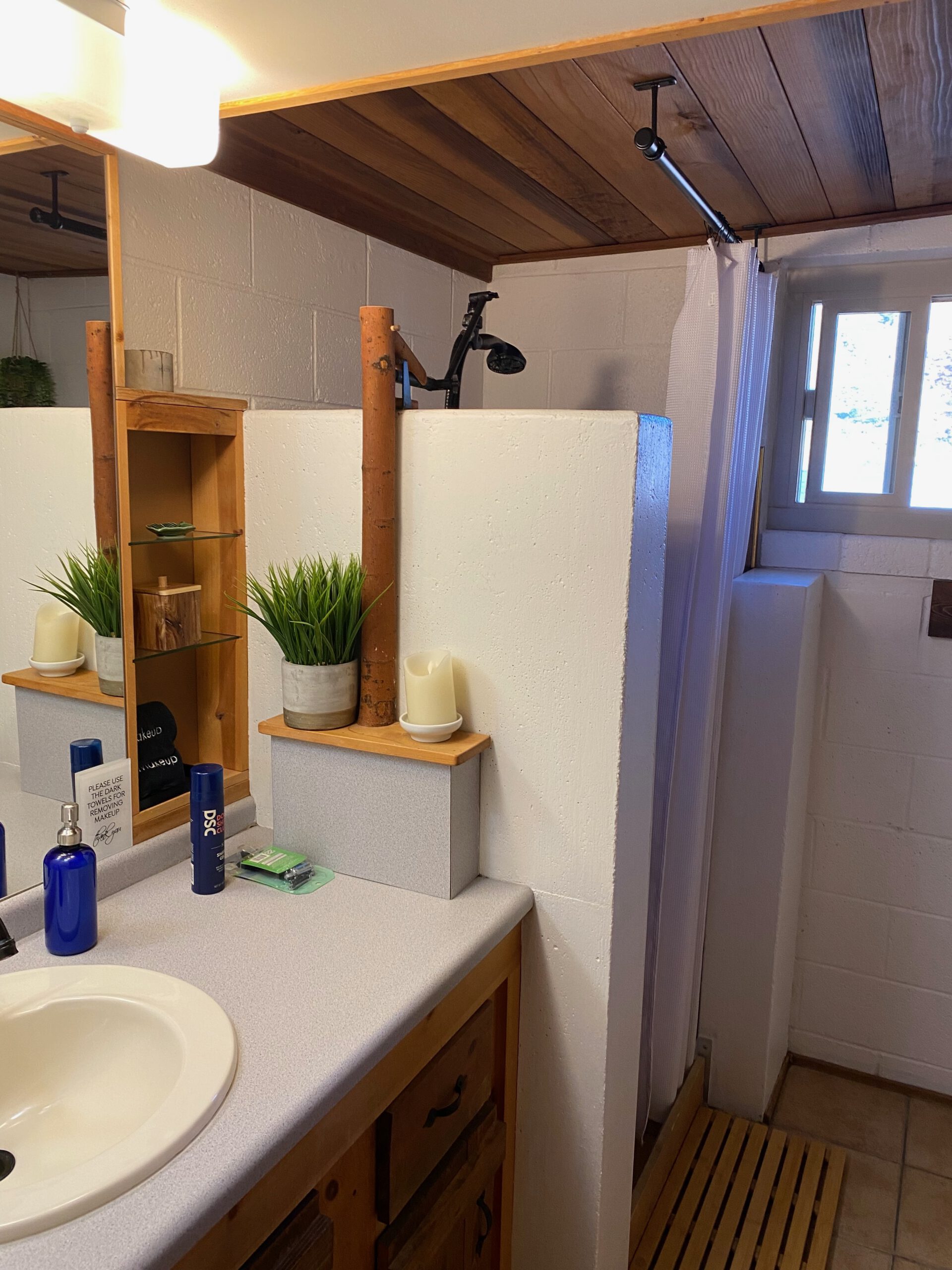 Bathroom at Casa Rustica Morongo Valley Airbnb with sink and vanity, open walk-in shower with curtain, wooden ceiling details, and simple rustic desert-style design.