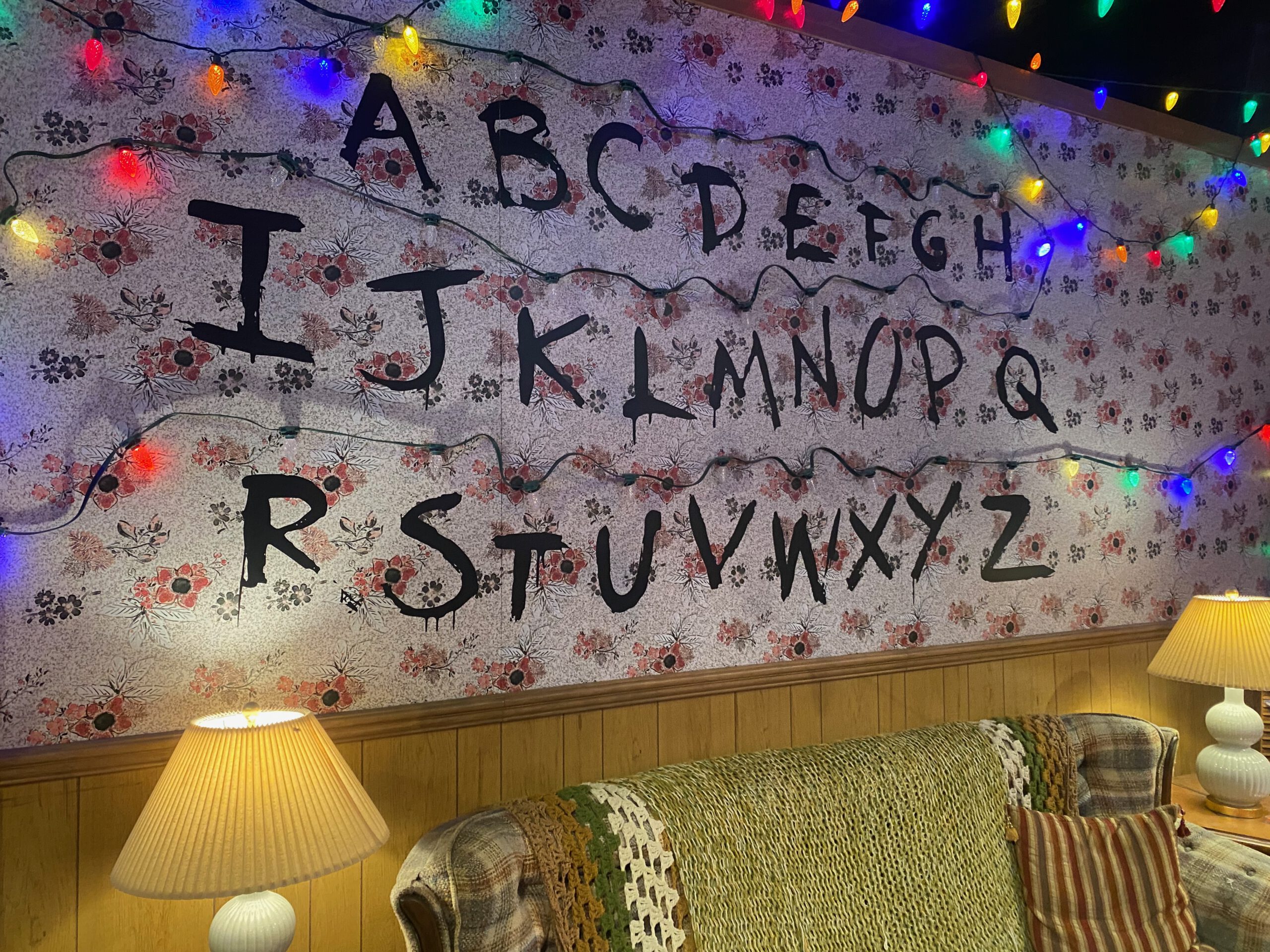 Close-up of the iconic Byers House alphabet wall with hand-painted letters and multicolored Christmas lights inside the Stranger Things Store Las Vegas Strip, recreating the Upside Down communication scene.
