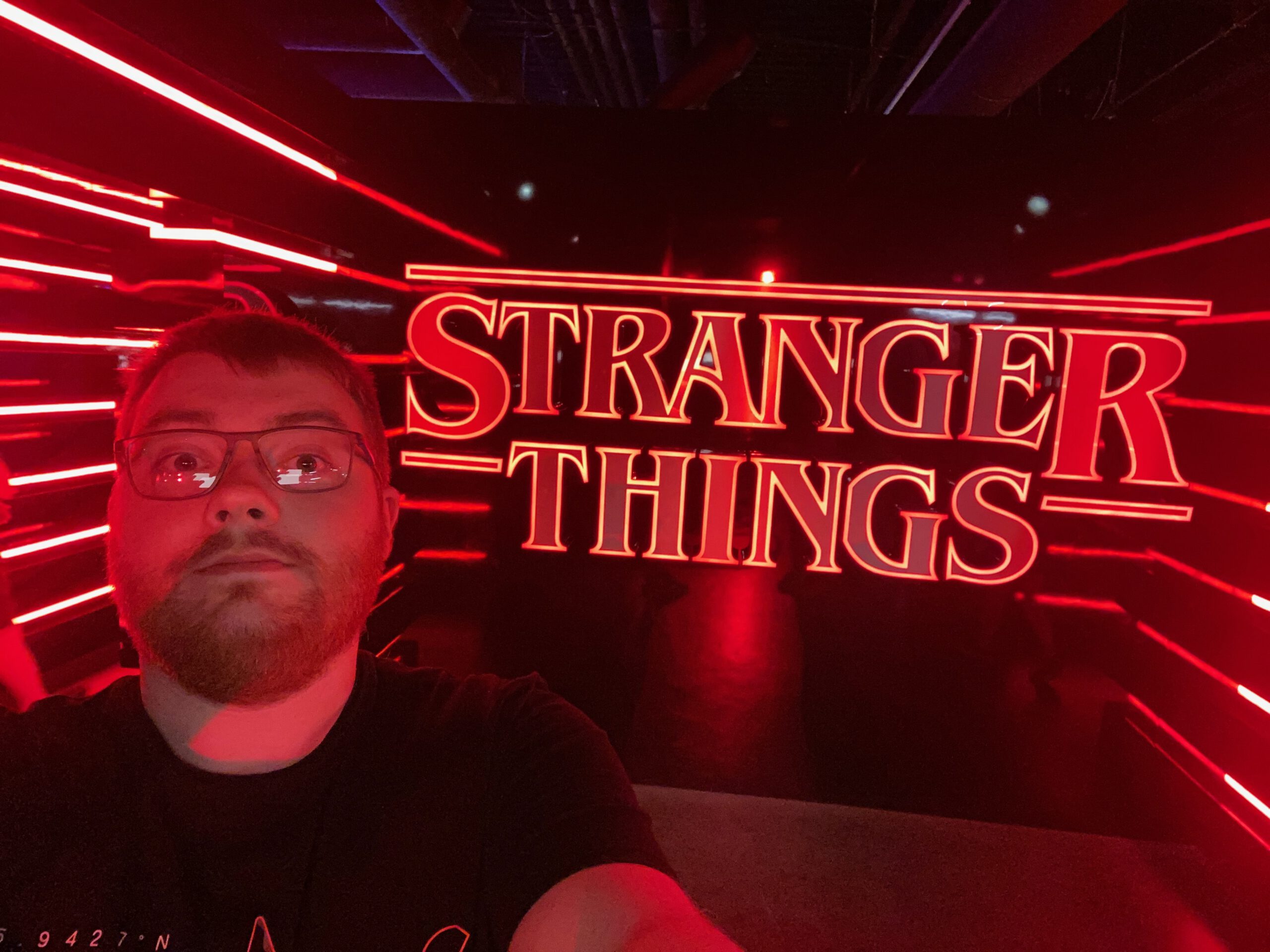 Visitor taking a selfie in front of the glowing red Stranger Things logo inside the Stranger Things Store Las Vegas Strip, surrounded by dramatic neon lighting inspired by the Upside Down.