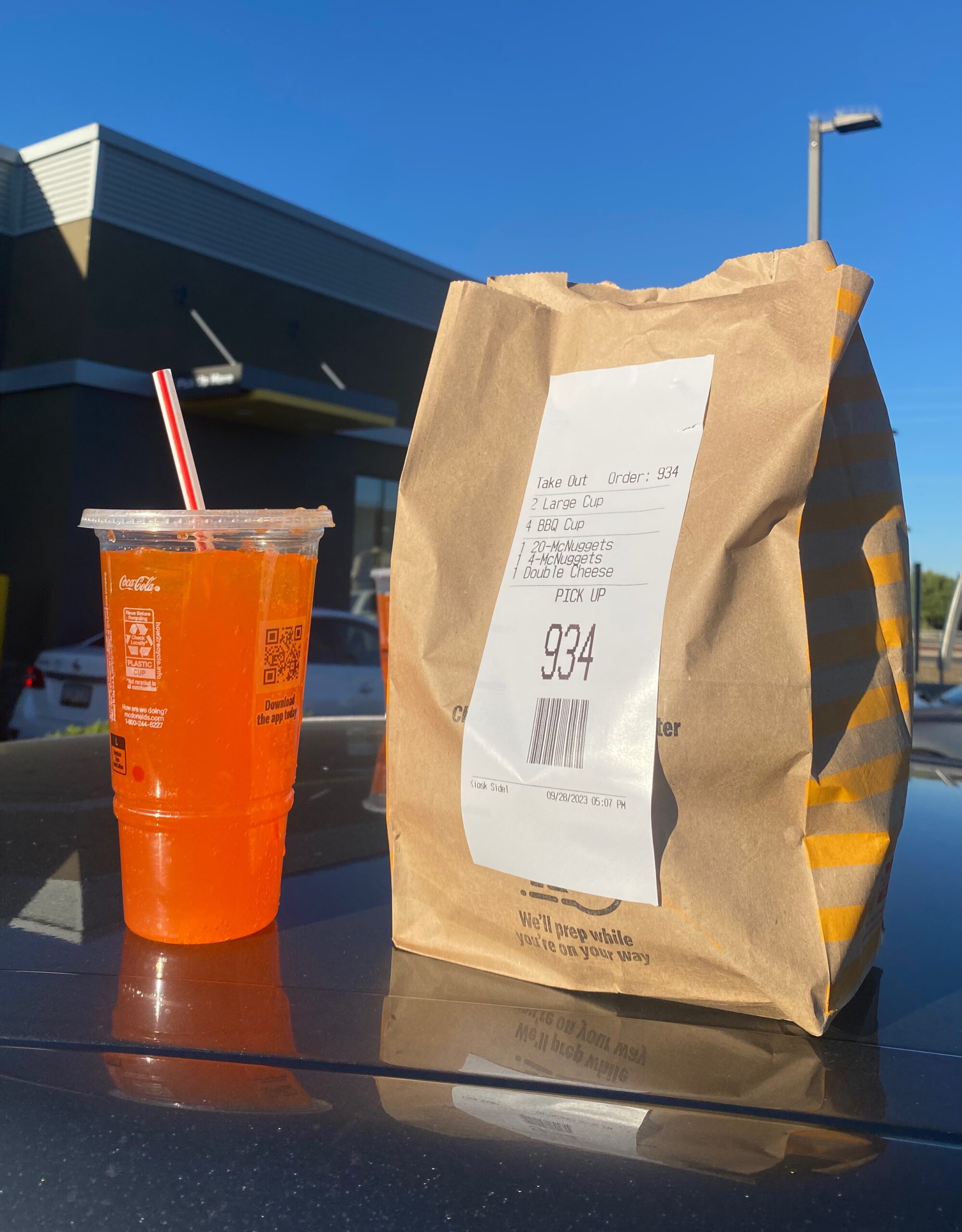 McDonald’s takeout bag (number 934) with McNuggets and large soda on car hood at McDonalds in Williams Arizona during a road trip stop near Grand Canyon