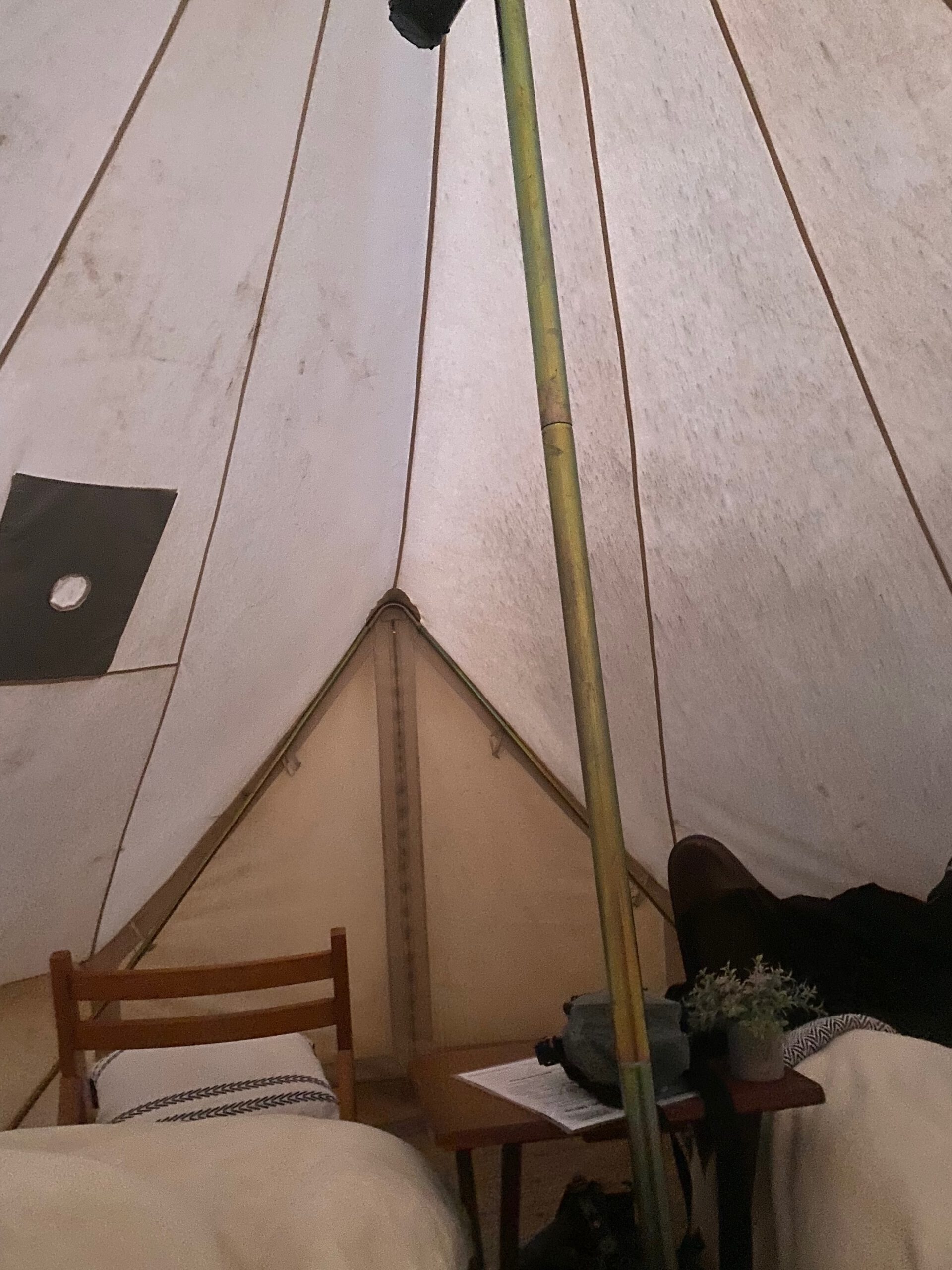 Inside a Wander Camp Grand Canyon glamping tent showing the canvas structure, central support pole, and simple off-grid interior under soft evening light.