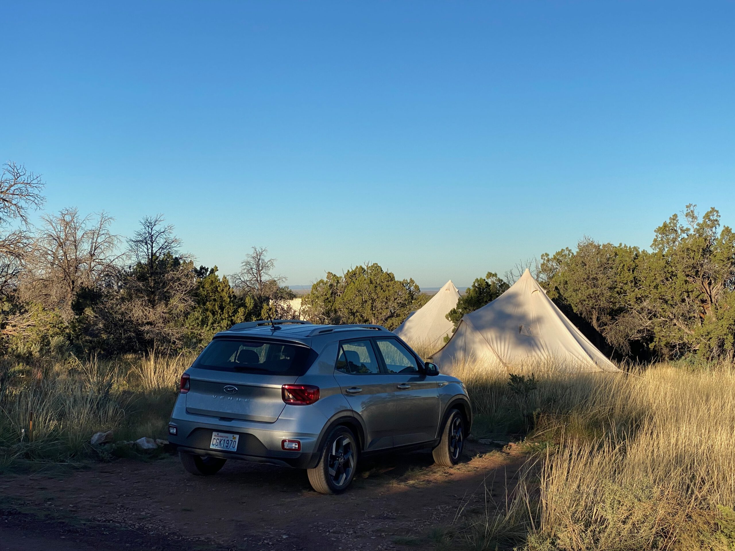 Car parked directly in front of a Wander Camp Grand Canyon glamping tent at sunset, showing private parking and off-grid camping in the Arizona wilderness