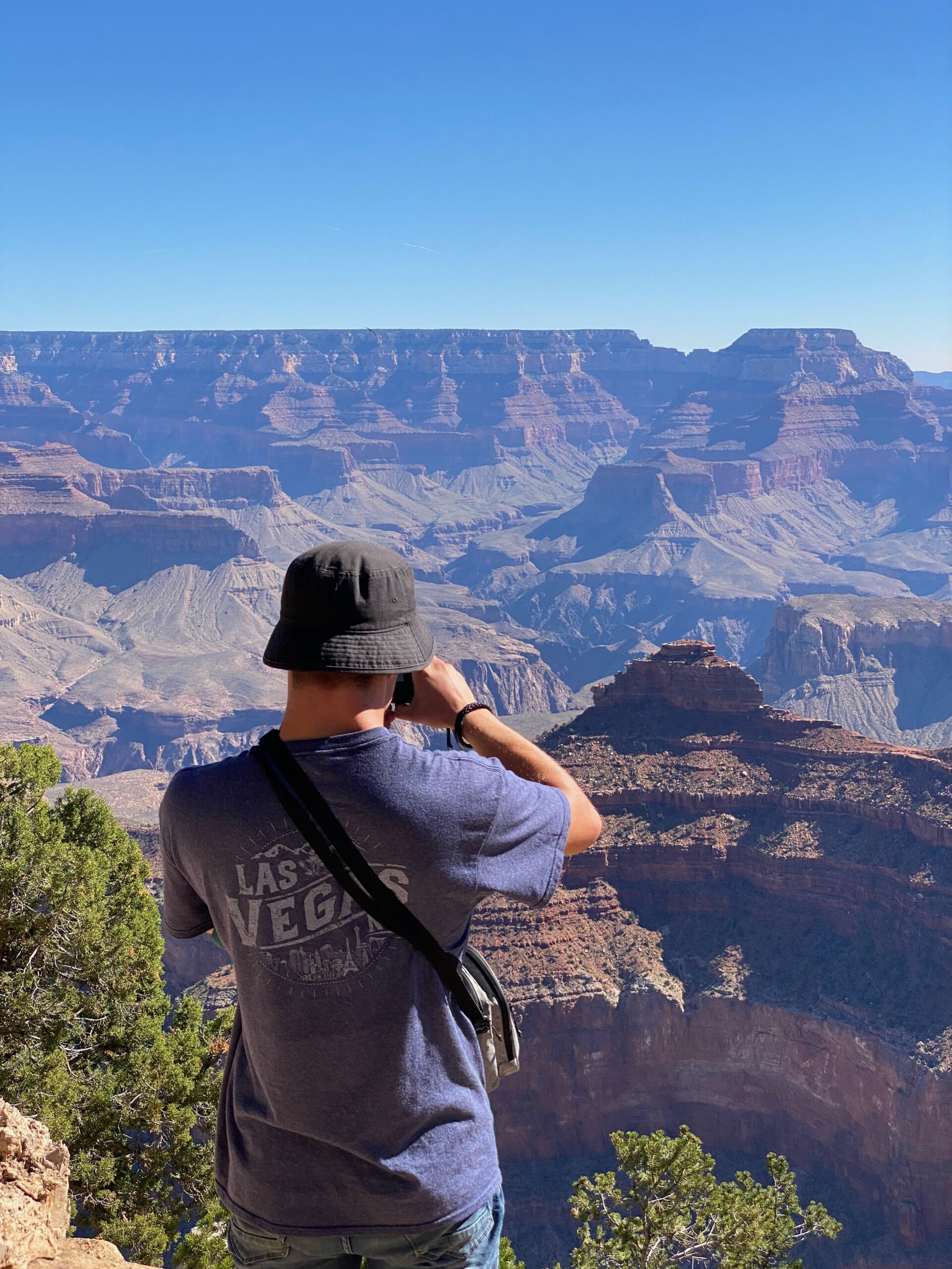 Traveler photographing the vast landscape of the Grand Canyon from the South Rim on a clear day
