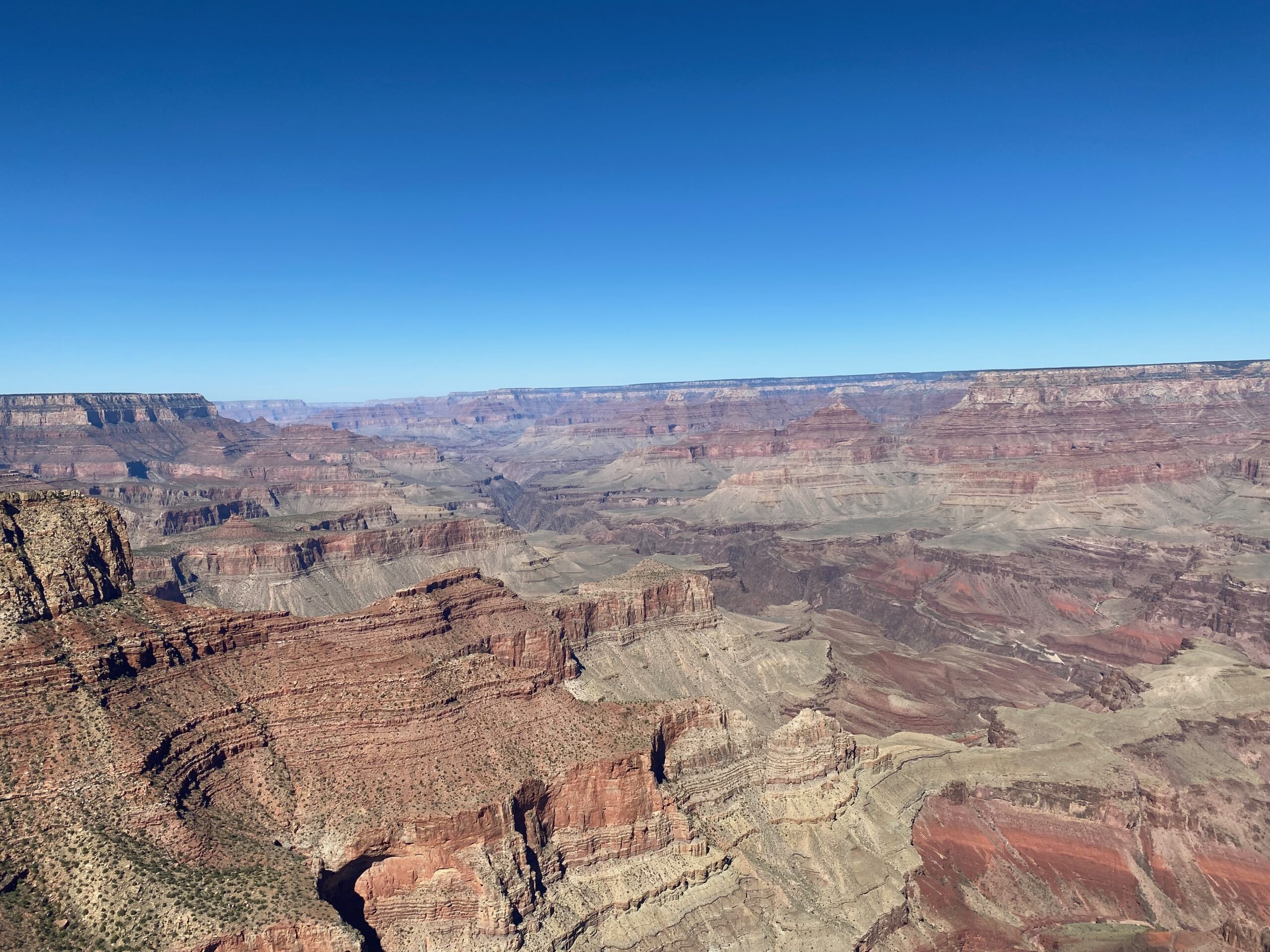 Panoramic landscape of Grand Canyon National Park from the South Rim with vast cliffs, plateaus, and desert terrain stretching into the distance