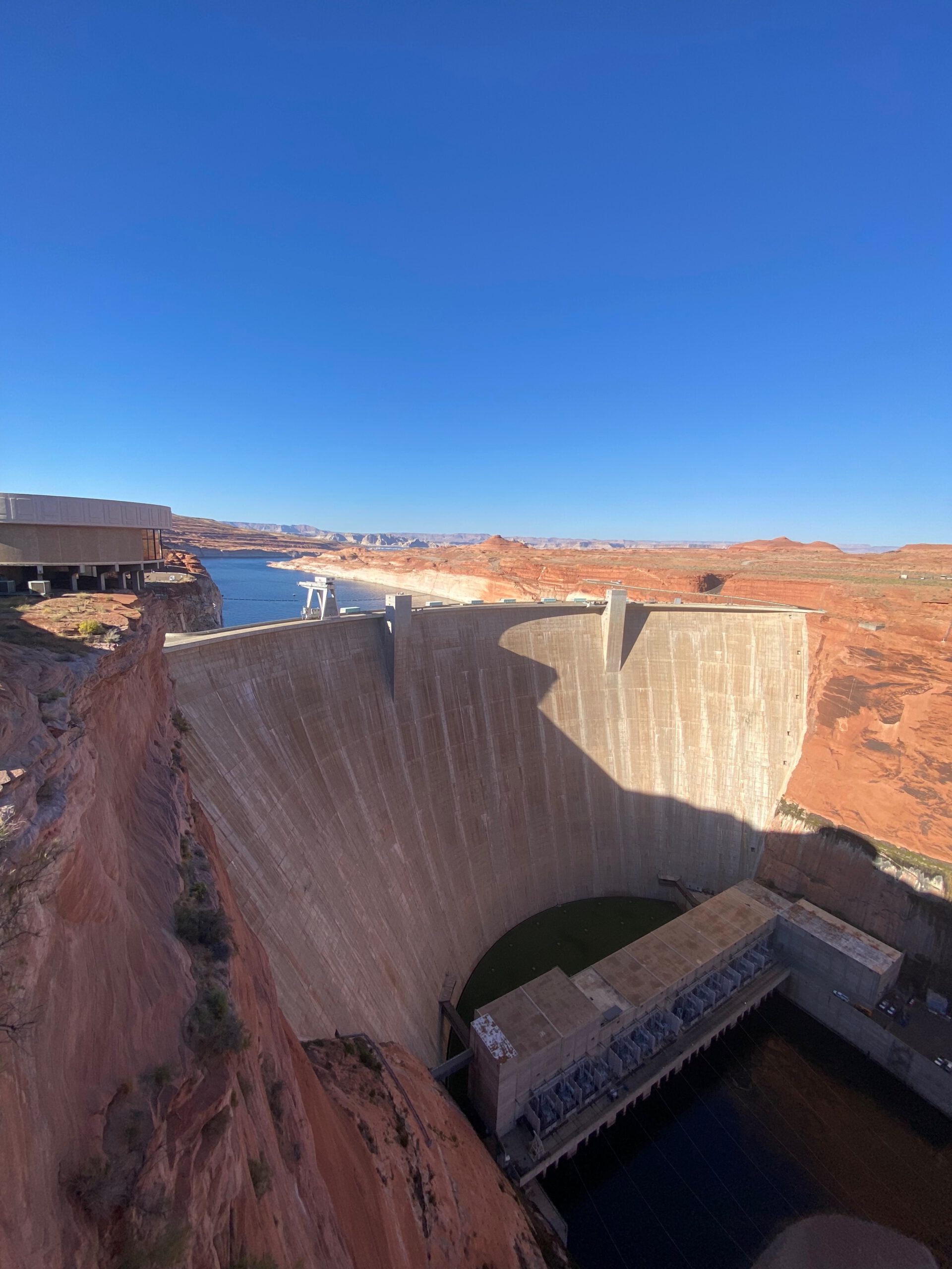 Glen Canyon Dam seen from the overlook, massive curved concrete dam with Lake Powell and red rock canyon scenery under a clear blue sky near Page, Arizona