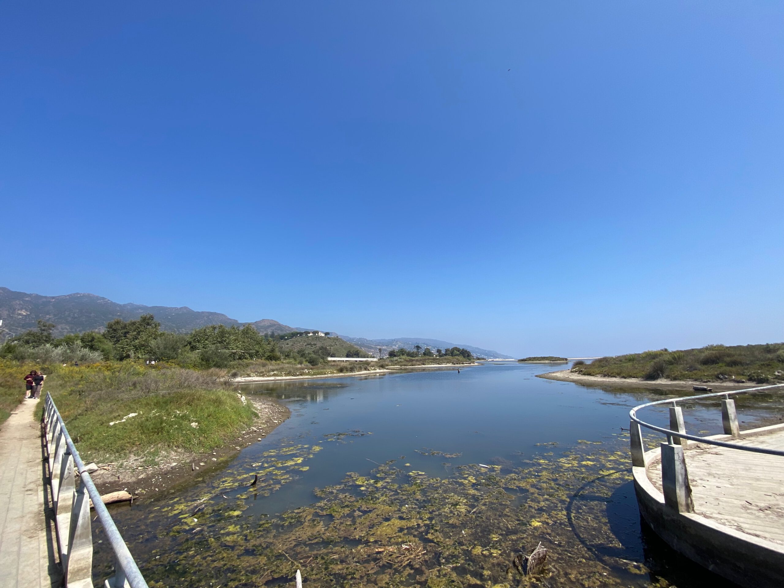 View over Malibu Lagoon with calm water, walking paths, and surrounding hills near Malibu Lagoon State Beach
