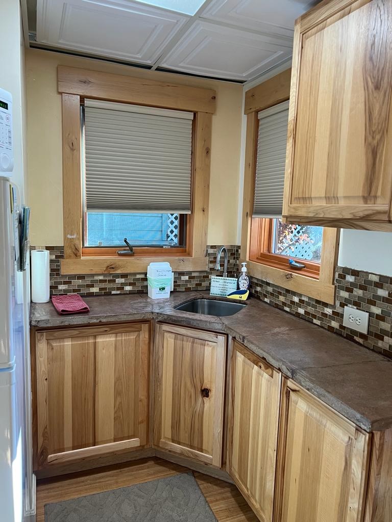 Compact kitchenette with wooden cabinets and sink inside a Lake Tahoe studio rental, featuring natural light, rustic finishes and a cozy interior suited for short stays near Tahoe Vista.