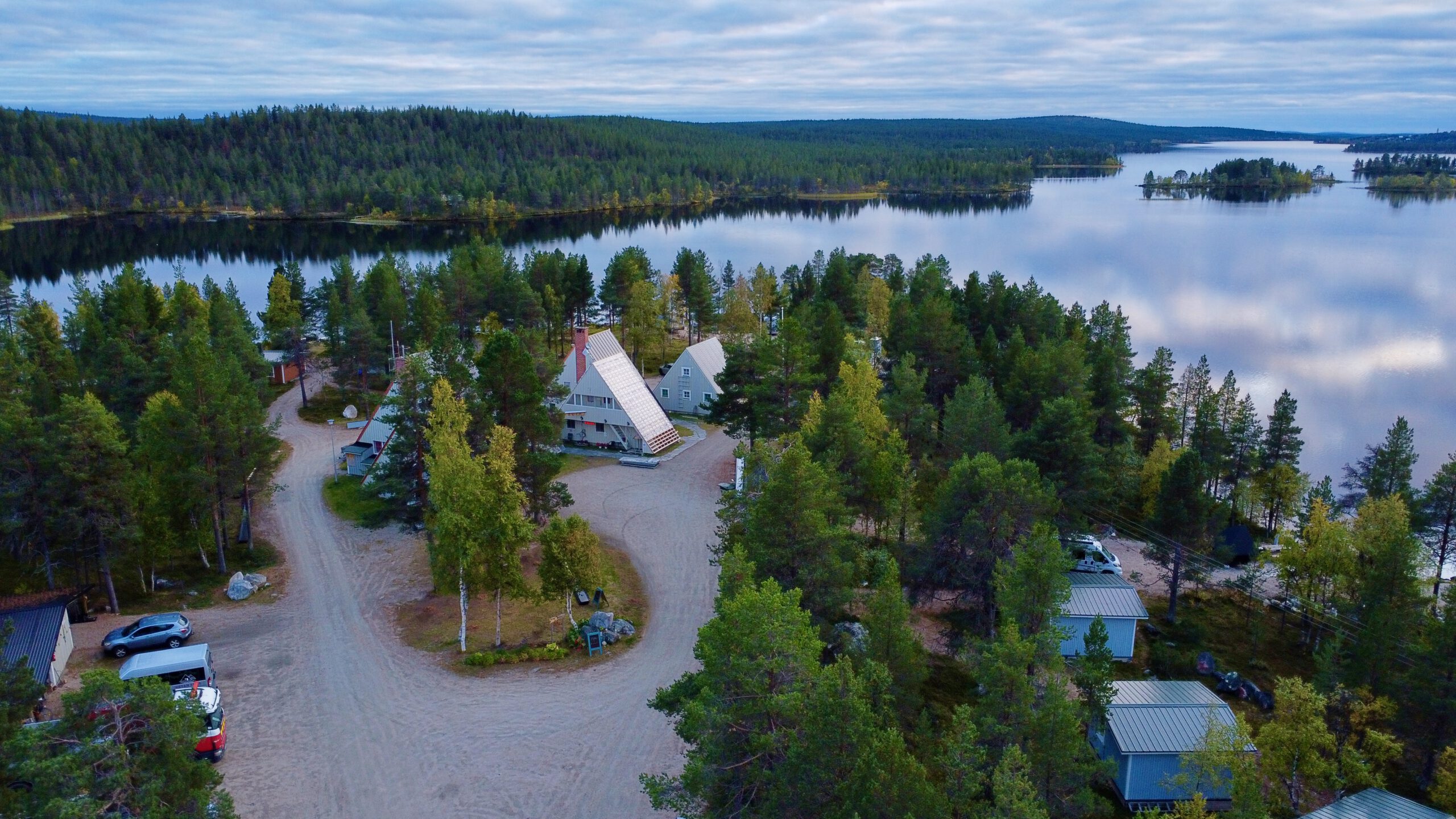 Hetan Kota Enontekiö Finland aerial view showing cozy triangular cabins surrounded by forest and lake in remote Lapland wilderness