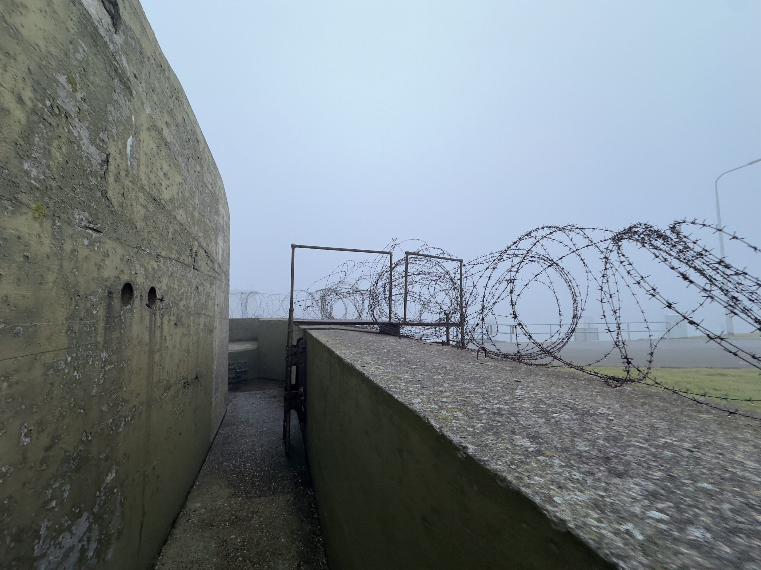 Walking Kornwerderzand beside Kazemat V, showing concrete World War II bunker walls and barbed wire
