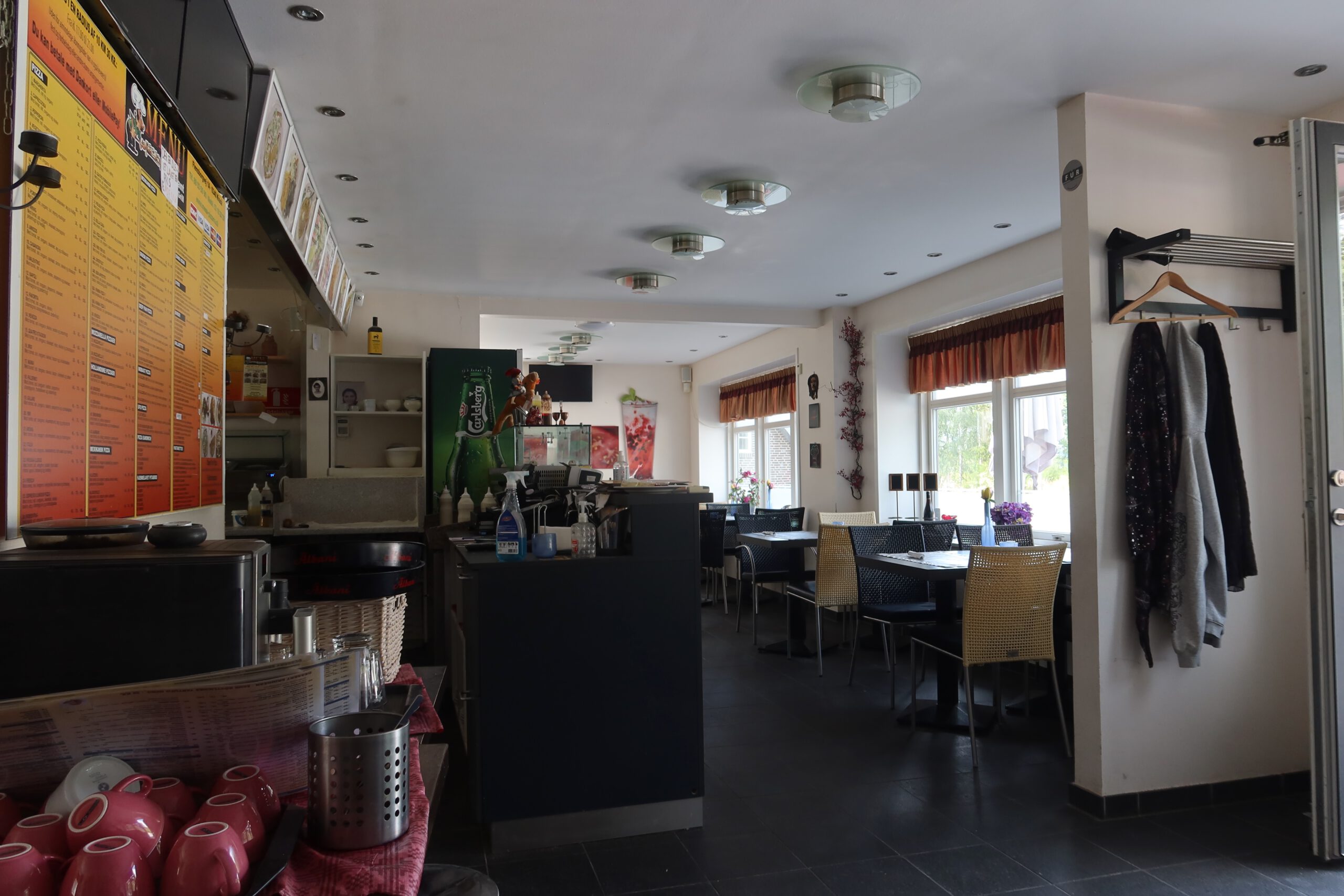 Interior of Menu Pizzeria & Grill Kruså, quiet dining area with menu boards and seating near the Danish German border