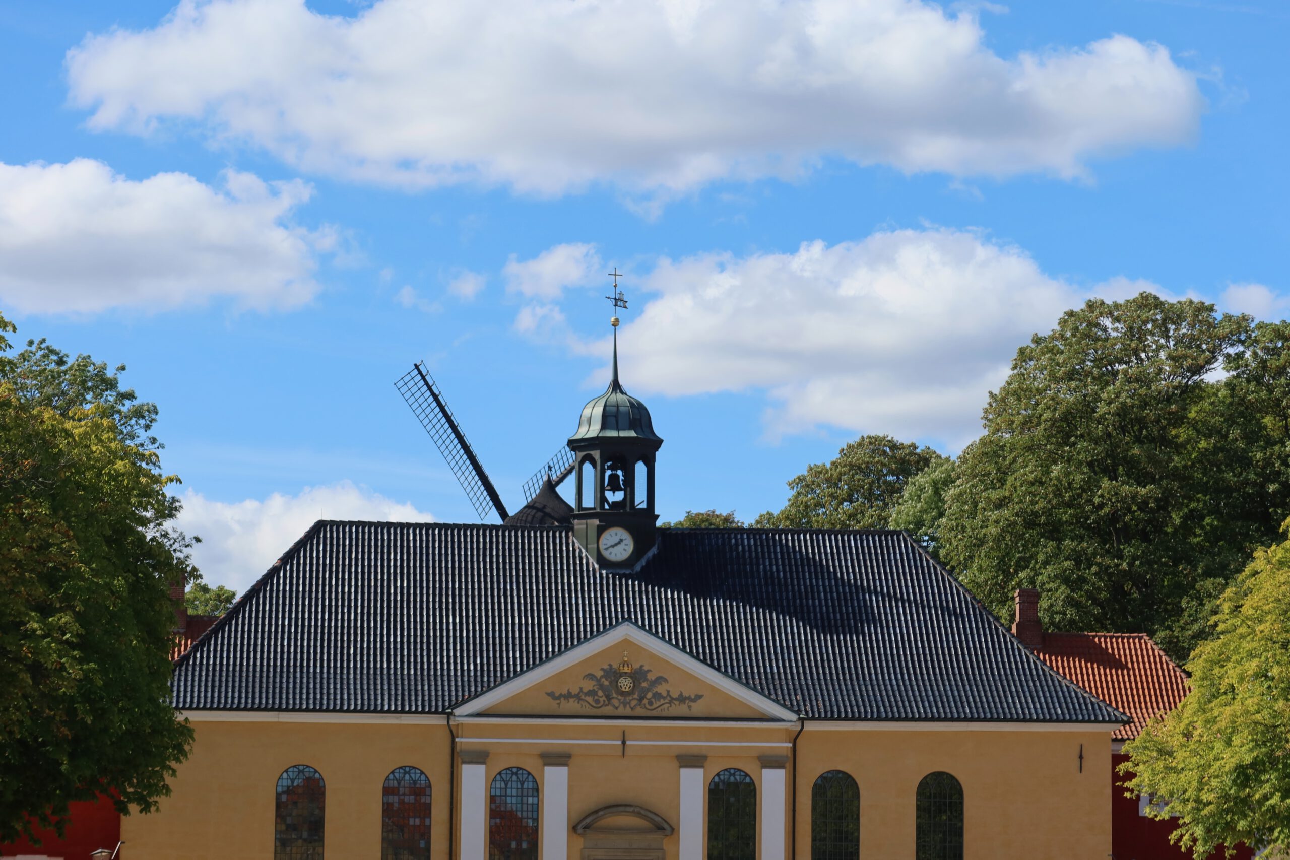 Kastellet Copenhagen church with historic yellow facade, clock tower and windmill rising above the star fortress grounds