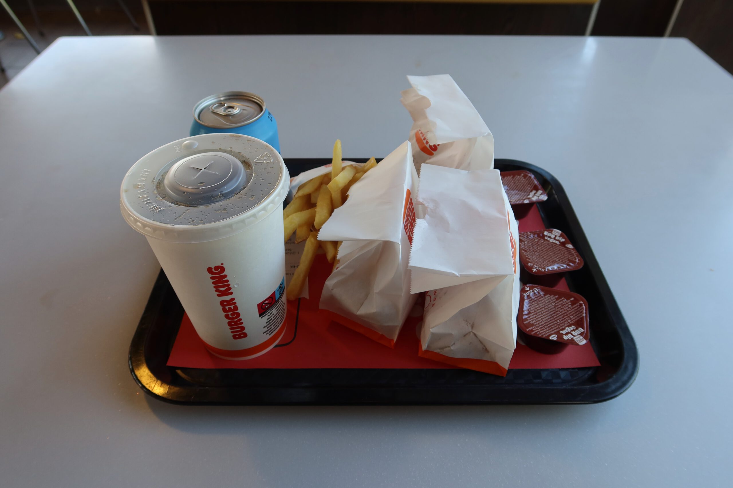 Burger King Malmö Ollebo meal with chicken nuggets, fries, barbecue sauce, Cola in a paper cup, and a Pripps Blå beer on a tray inside the restaurant