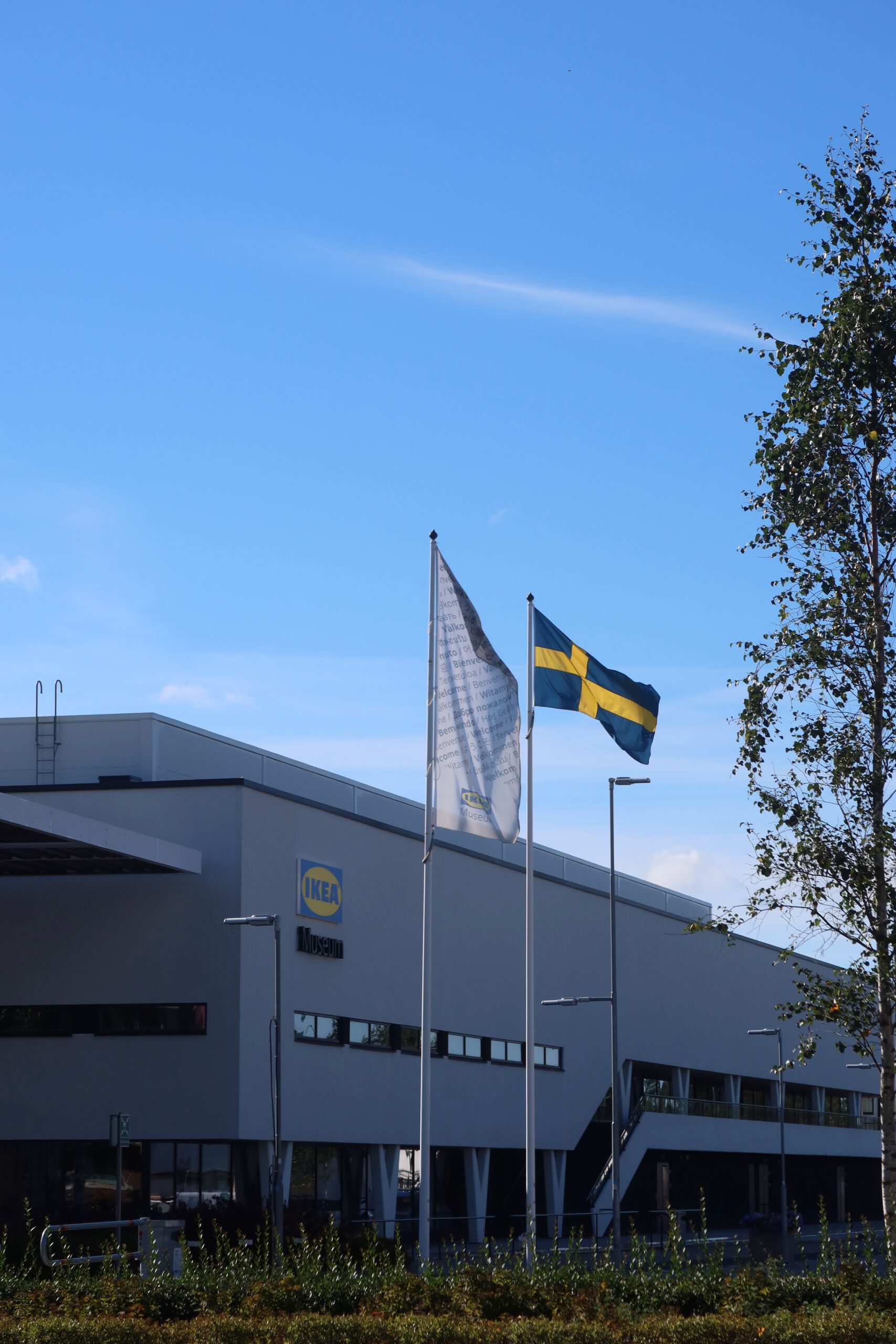 IKEA Museum Älmhult exterior with Swedish flag and museum building under a clear blue sky in Småland, Sweden