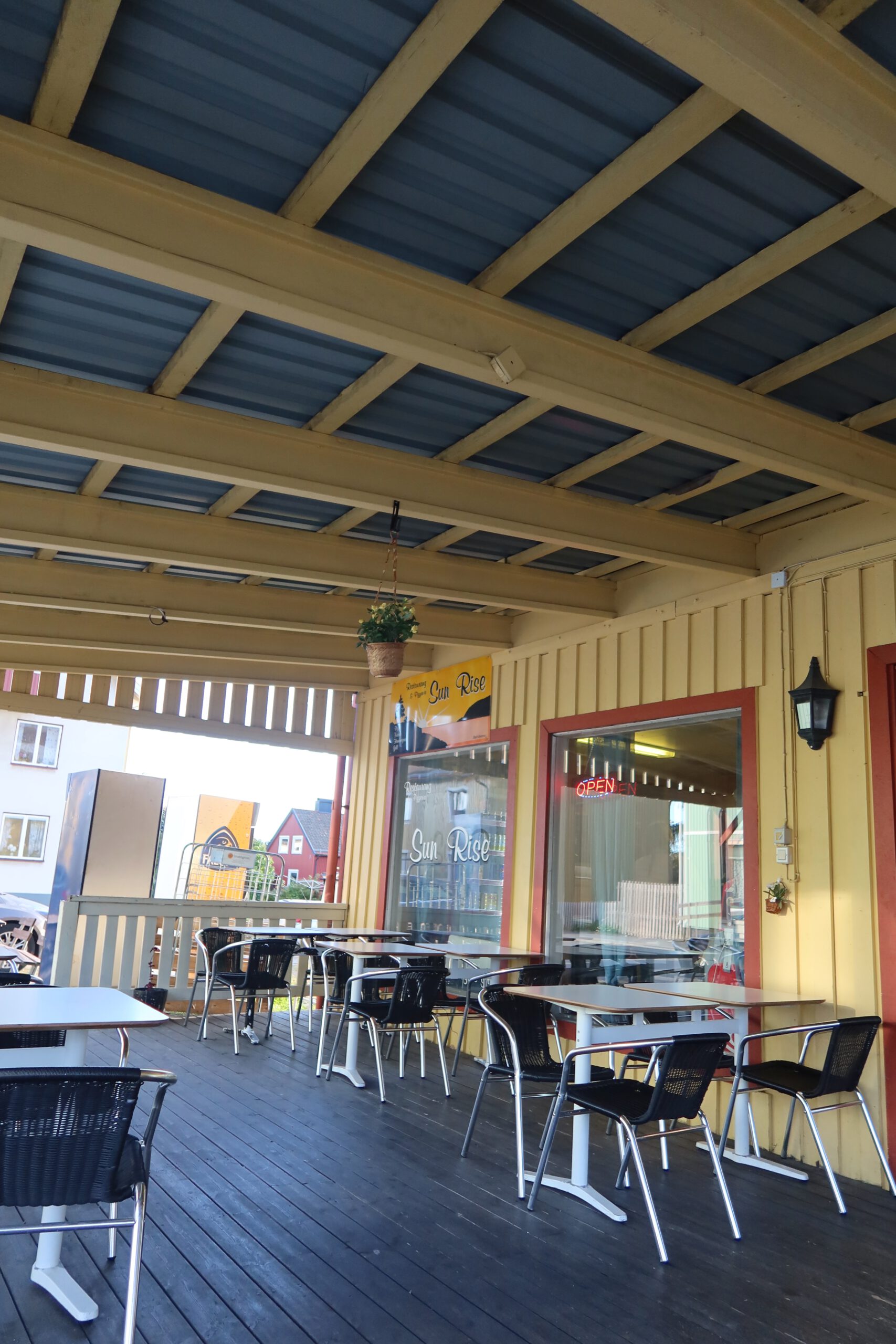 Sun Rise Nordmaling outdoor terrace with covered seating, empty tables and a calm roadside atmosphere during a Scandinavian road trip