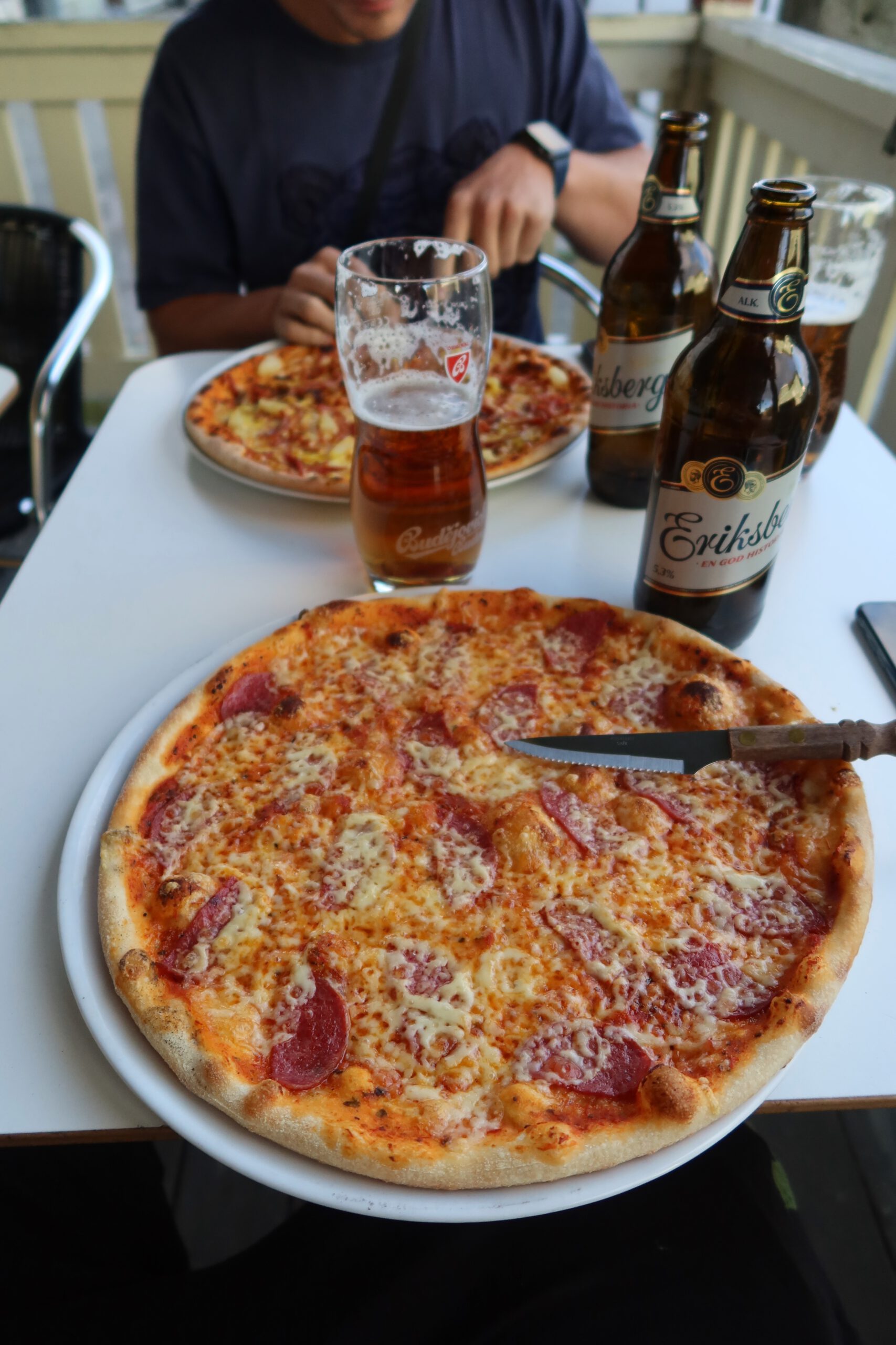 Sun Rise Nordmaling pizza dinner with a classic thin crust pepperoni pizza topped with melted cheese and salami, served outdoors during a Scandinavian road trip stop