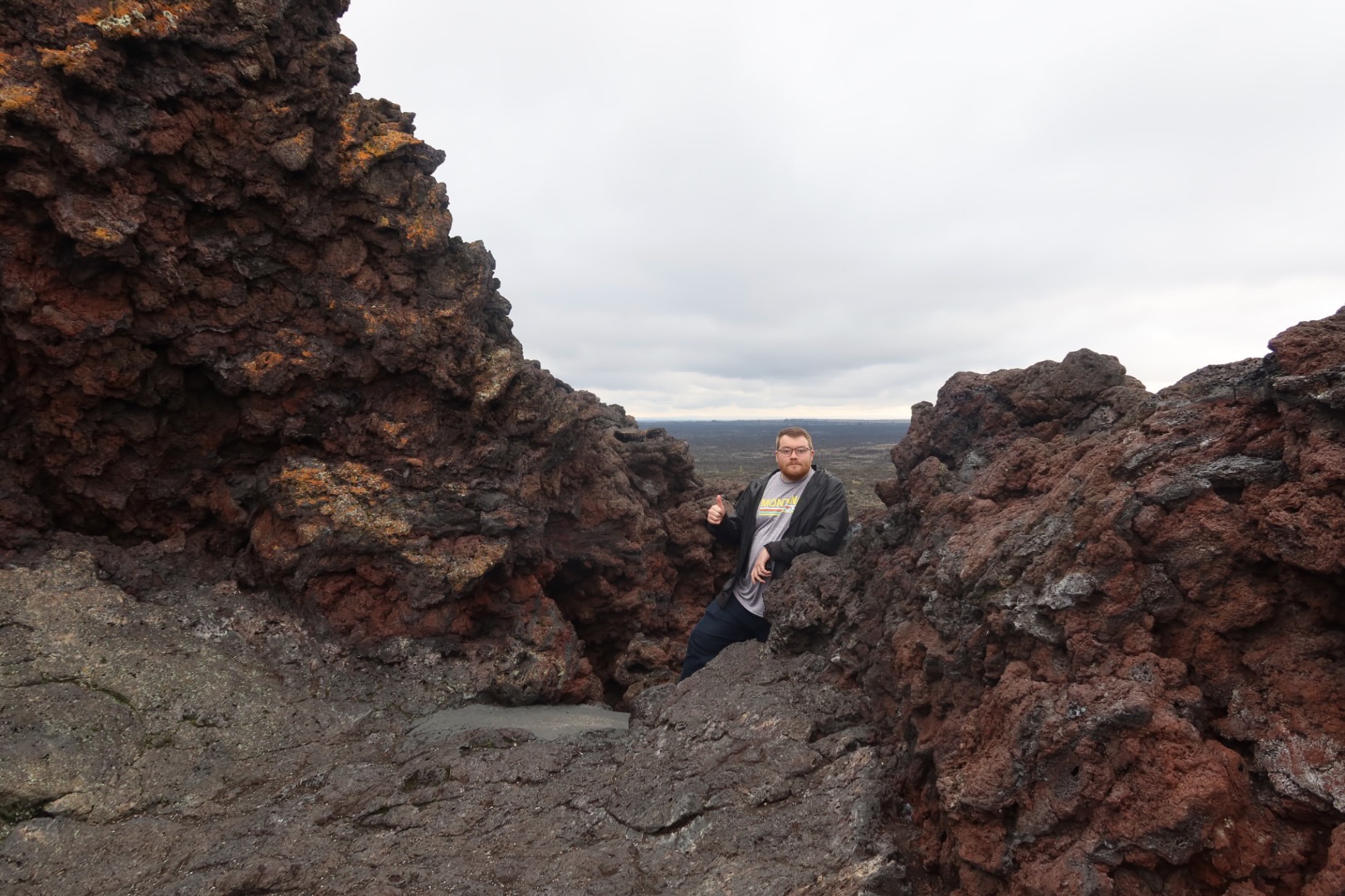 Standing between rugged lava rock formations near Indian Tunnel at Craters of the Moon National Monument in Idaho, surrounded by volcanic terrain