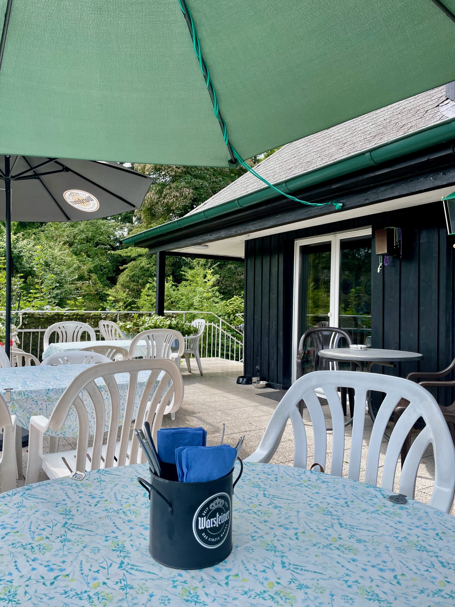 Kaffee Restaurant Hardt Stübchen Wuppertal outdoor terrace with white chairs, umbrellas, and peaceful green park surroundings