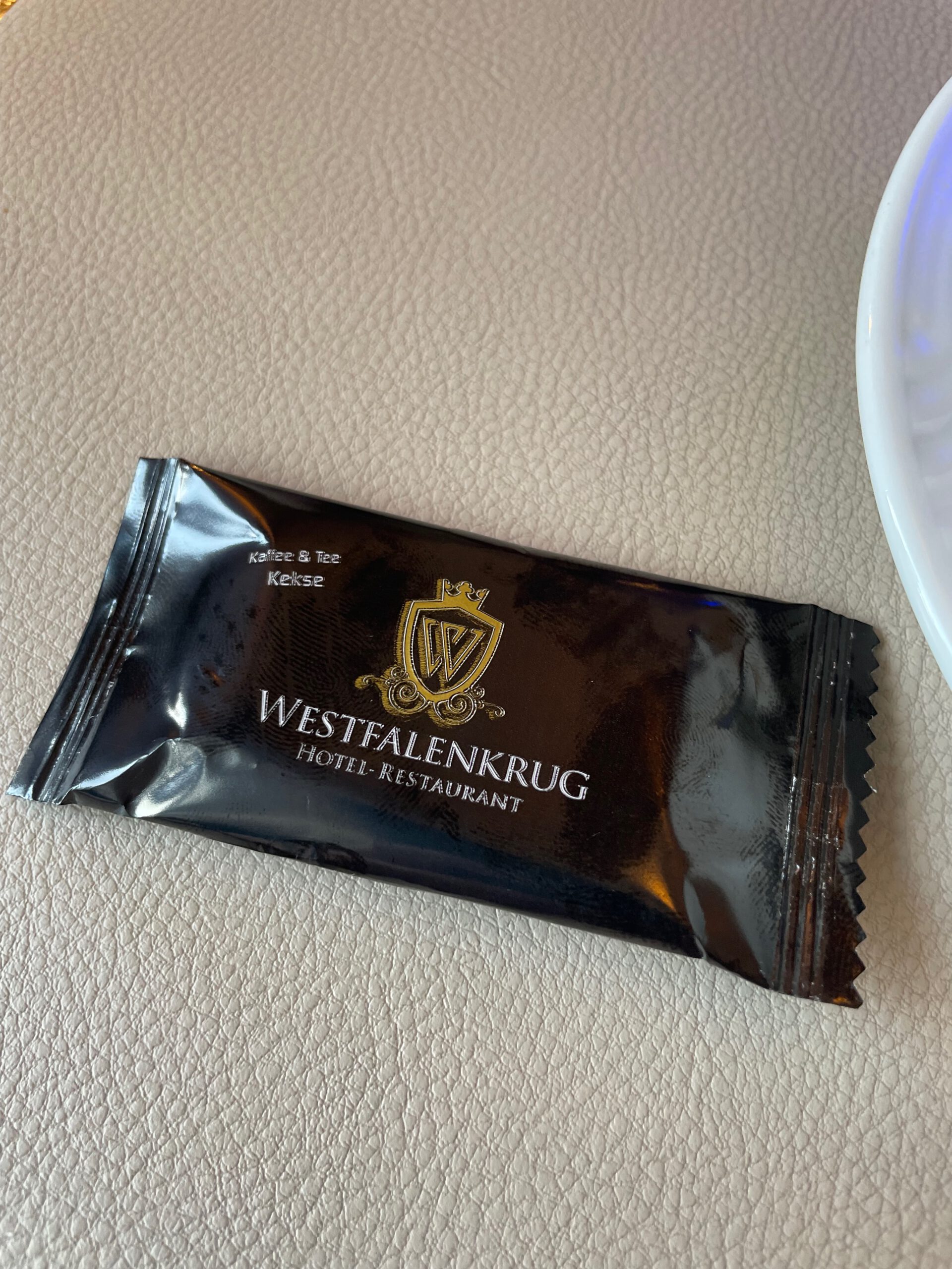 Complimentary cookie with Westfalenkrug Wuppertal hotel restaurant branding served alongside coffee