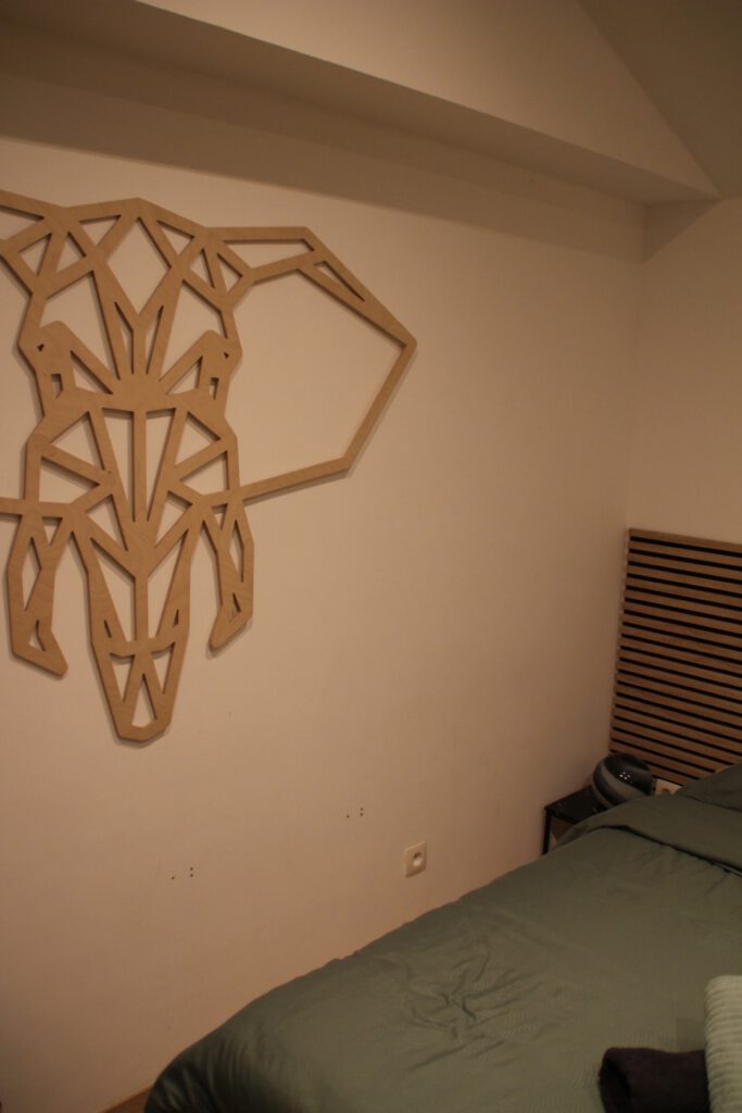 Le cocon de Chênée Liège bedroom interior, compact sleeping area with wooden wall art and minimal design