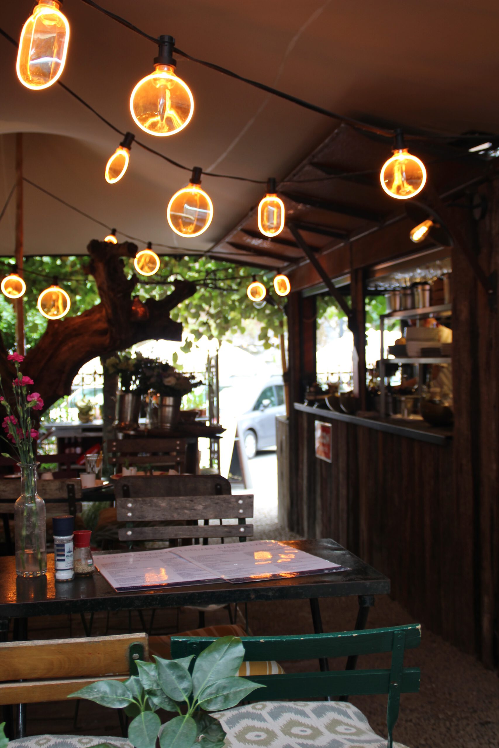 Edouard Garden Café Durbuy cozy outdoor terrace featuring rustic tables, ambient lighting, greenery, and a charming garden setting perfect for lunch or drinks