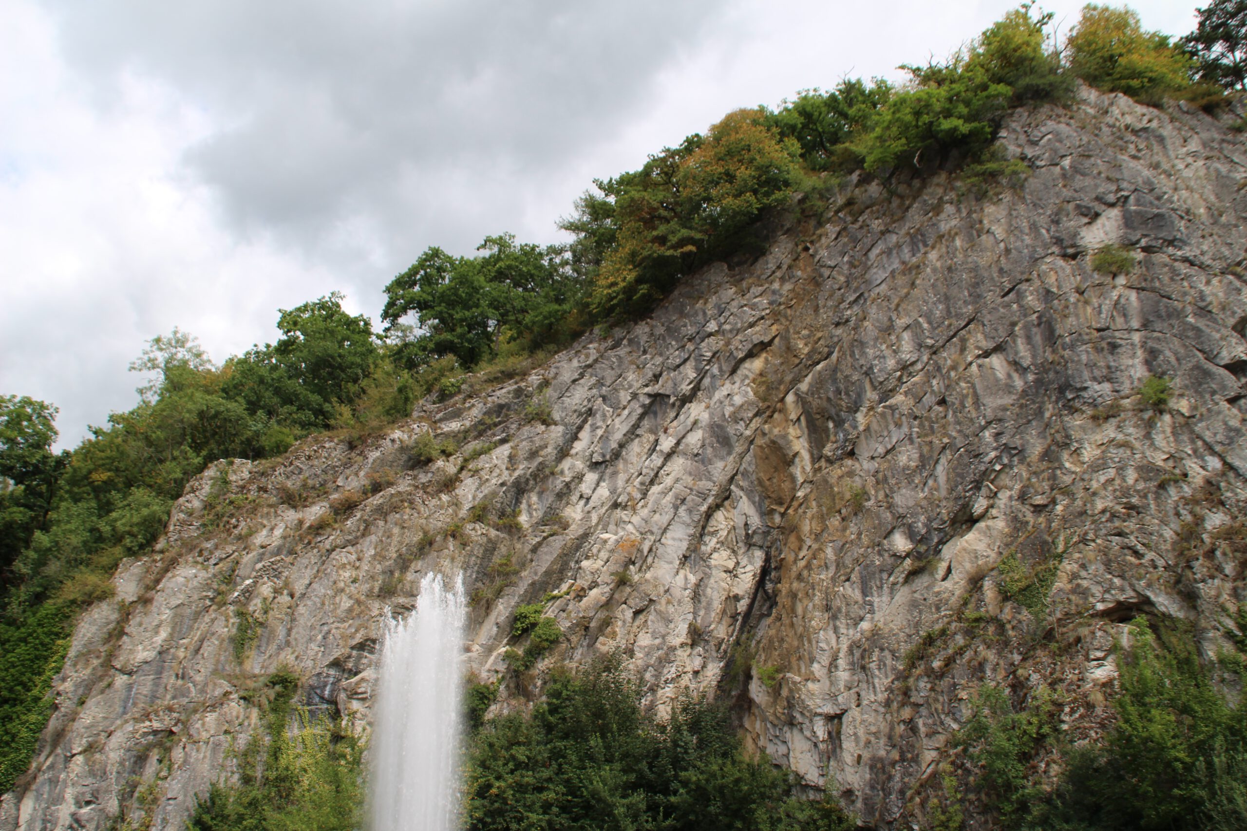 Durbuy travel experience featuring a dramatic rock cliff with a natural water fountain surrounded by greenery near the town