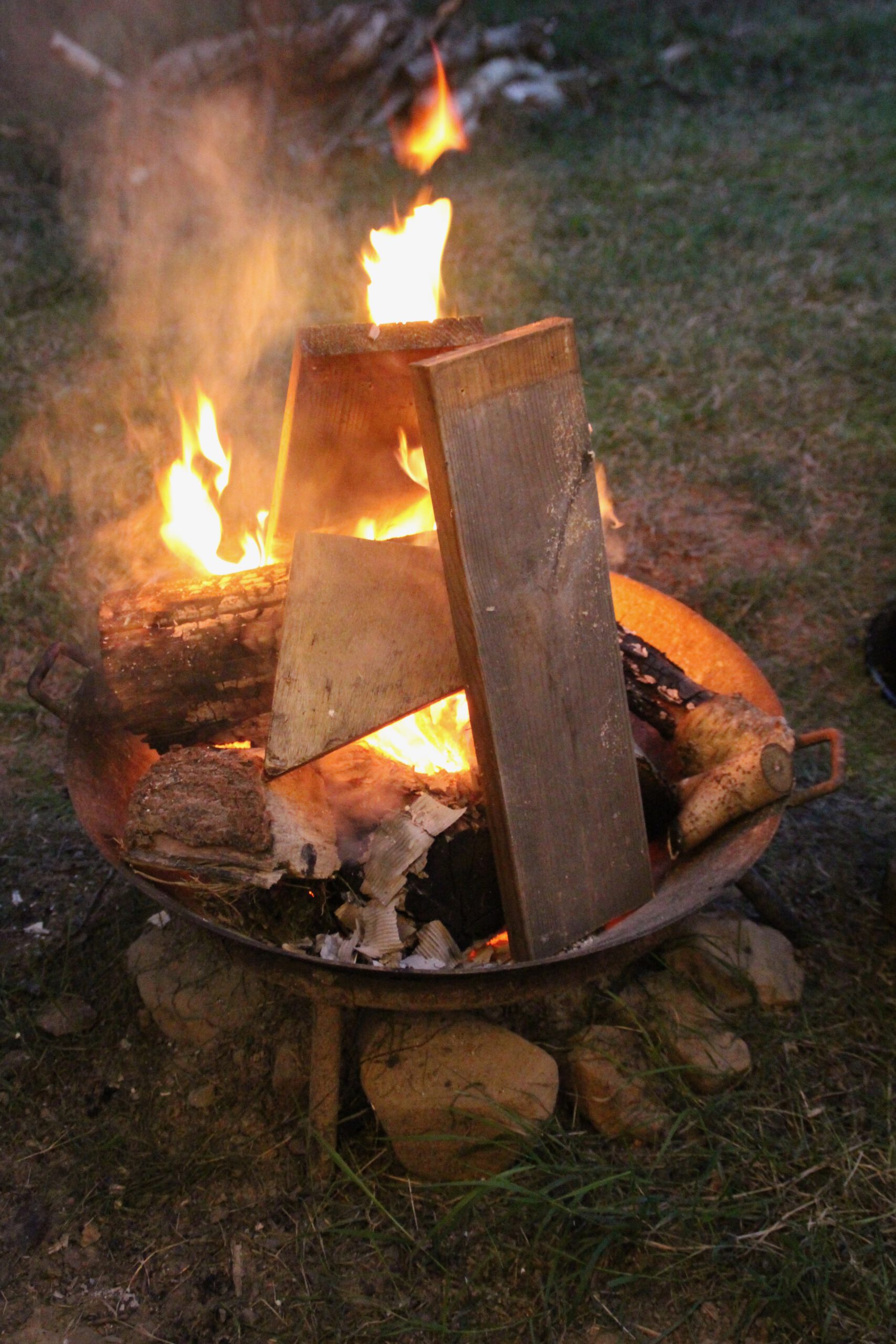 Josephine Caravan Aywaille rustic fire pit with stacked firewood providing evening warmth in a quiet forest setting in Belgium