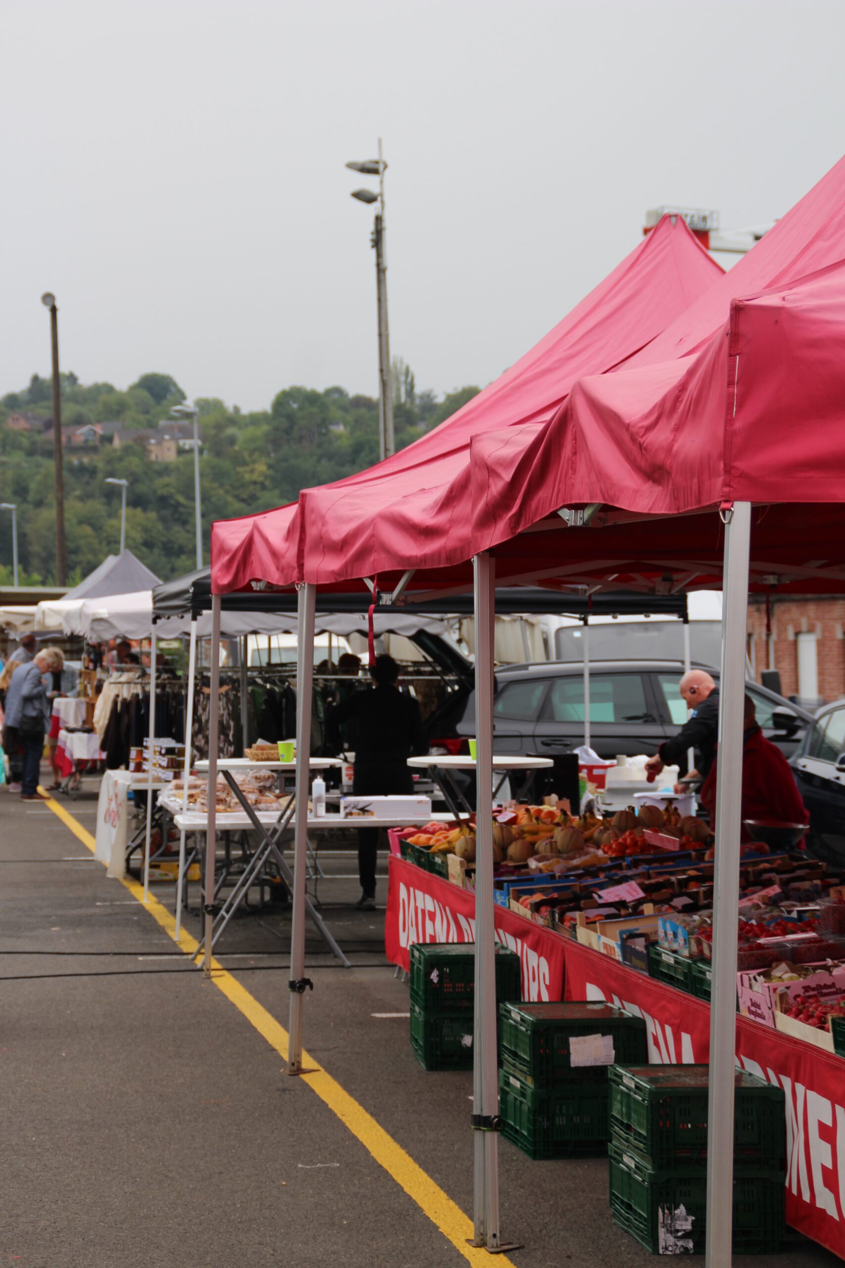 Outdoor stalls at the Aywaille Market located next to Aywaille Train Station, featuring fresh produce vendors and a lively local atmosphere