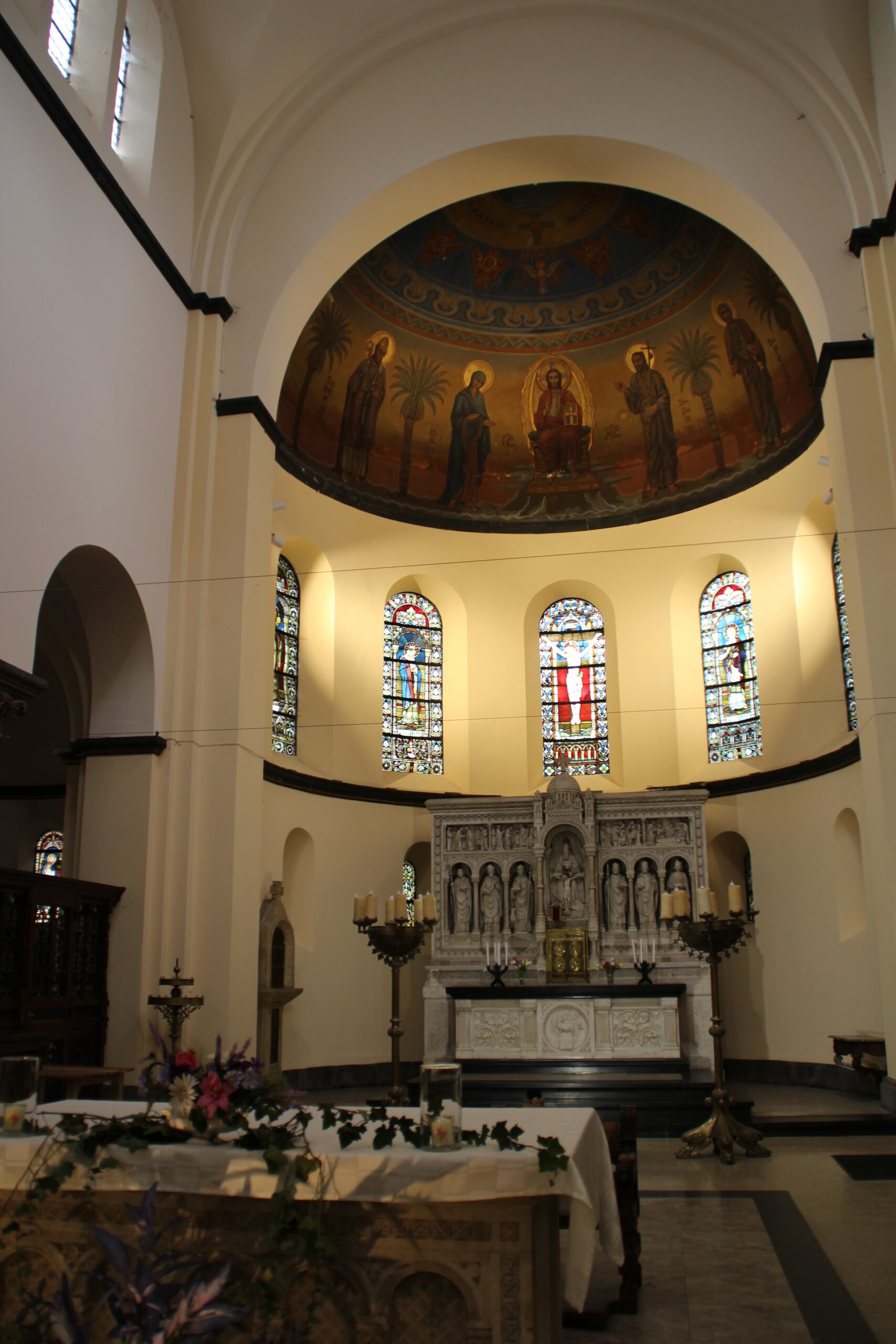 Saint Remaclus Church in Spa altar, detailed apse with religious murals and stained glass windows inside the Roman Catholic church in Spa, Belgium