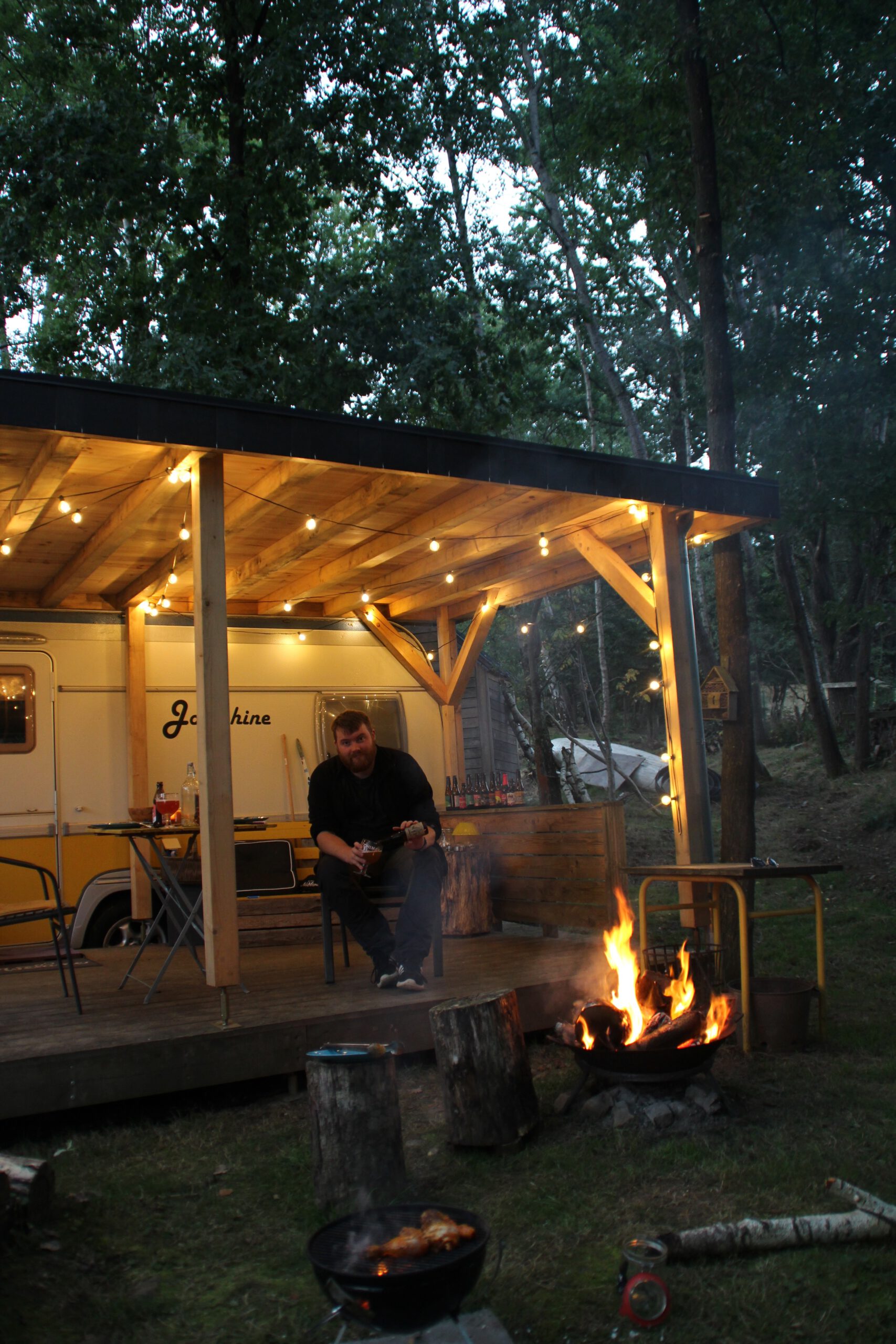 Josephine Caravan Aywaille Timo van den Berg enjoying a barbecue night by the outdoor fire pit on the forest porch in Belgium