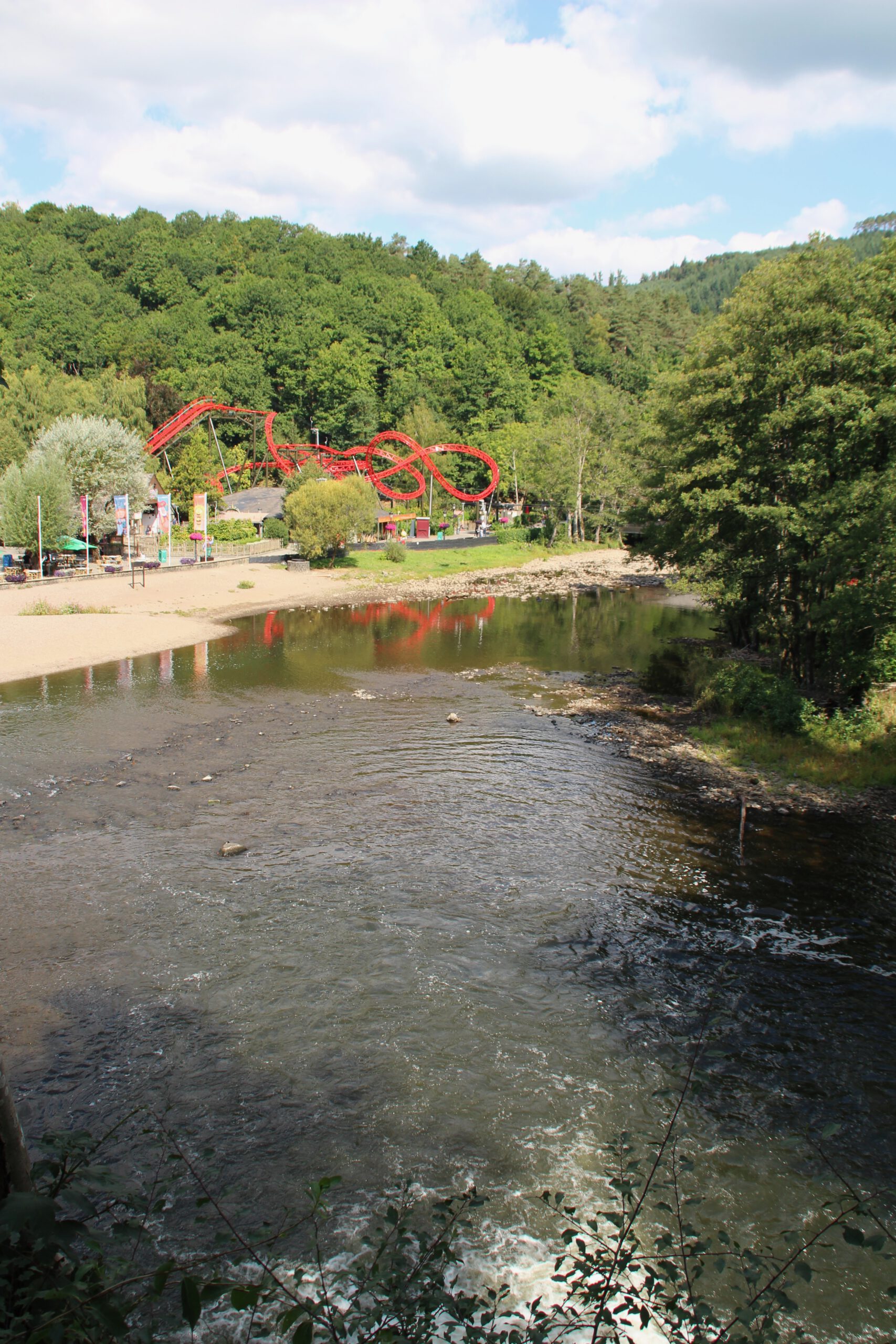 Watervallen of Coo overlooking Plopsaland Ardennes, wide view of the Amblève River with the amusement park and forested hills near Coo and Stavelot