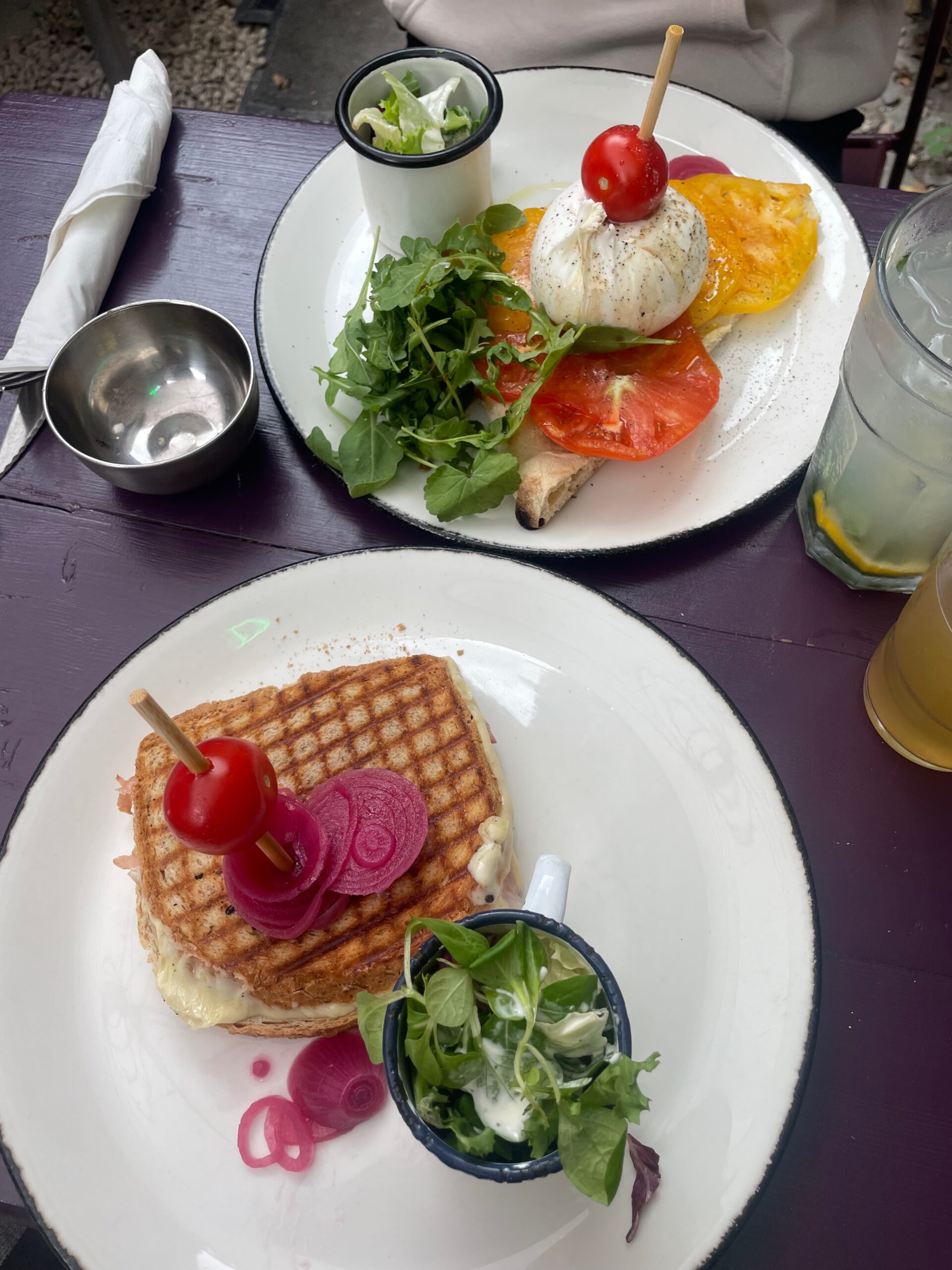 Edouard Garden Café Durbuy lunch dishes featuring croque monsieur style grilled sandwich, fresh salad, burrata toast, and colorful garden terrace presentation