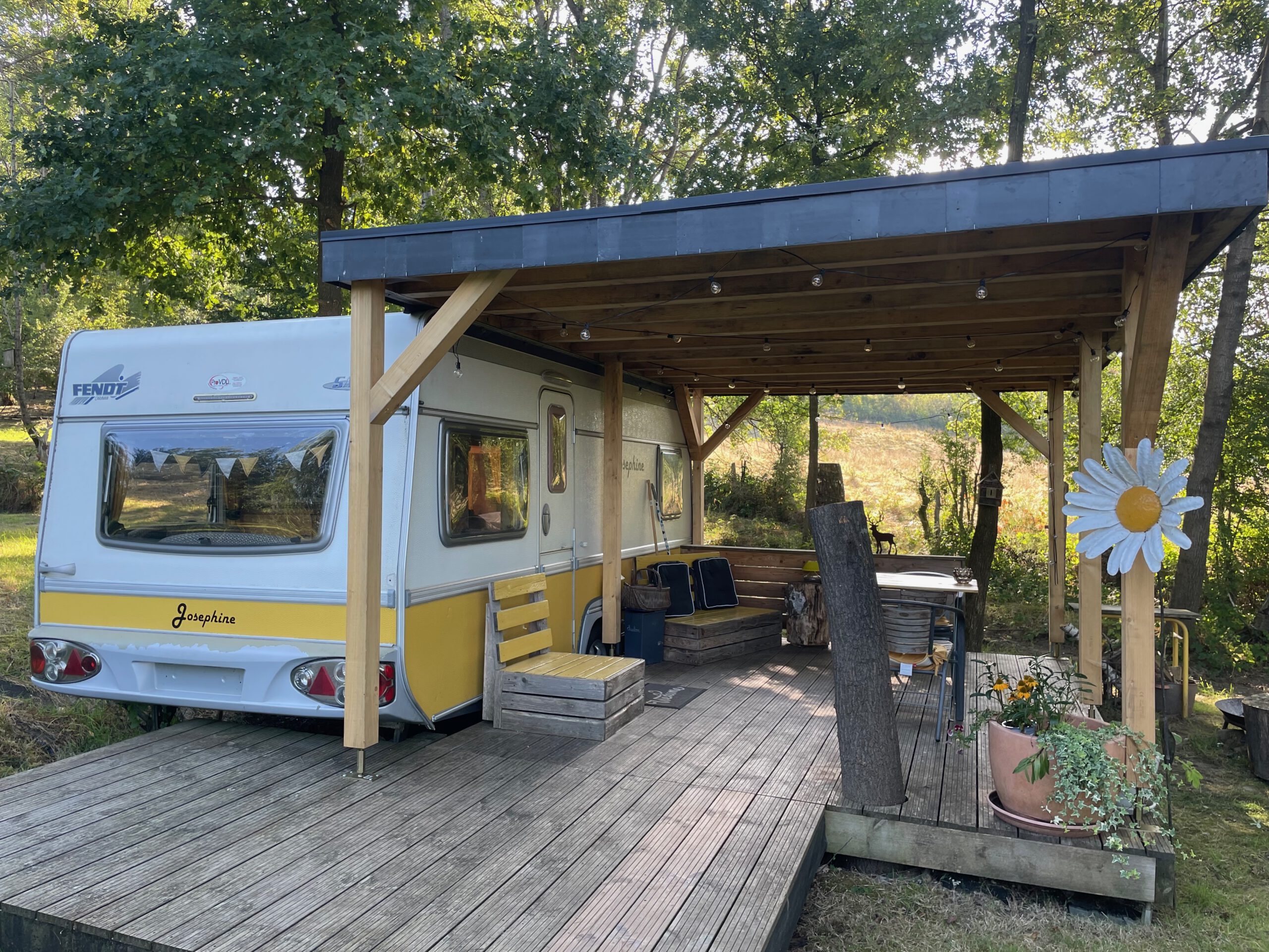 Josephine Caravan Aywaille renovated caravan with covered wooden terrace, outdoor seating, and forest surroundings in the Belgian Ardennes