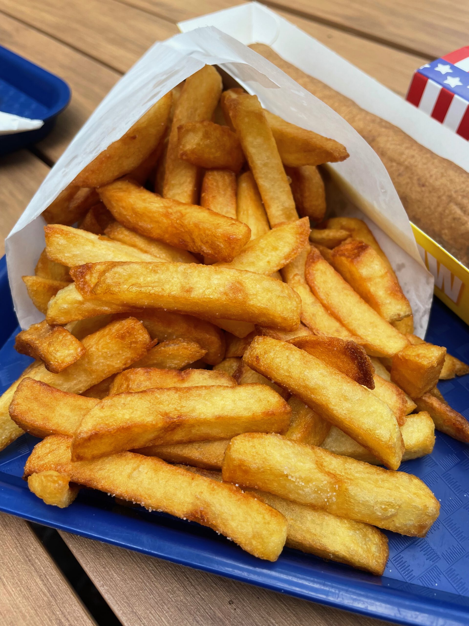 Chez Flo lunch review featuring a close up of crispy Belgian fries served in a paper cone on a blue tray