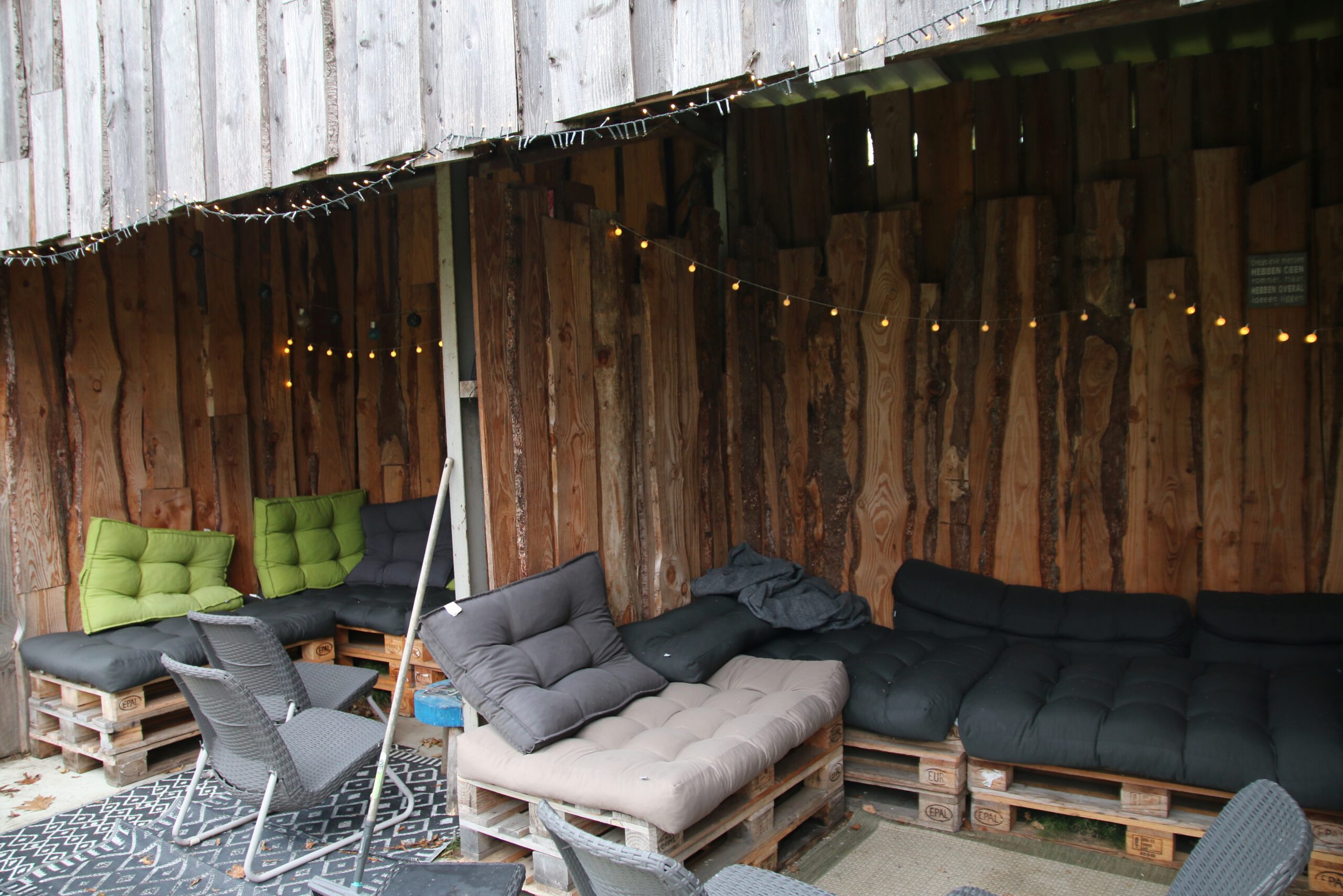 Back To Basic Zwaanshoek outdoor seating area with pallet sofas, cushions and warm string lights