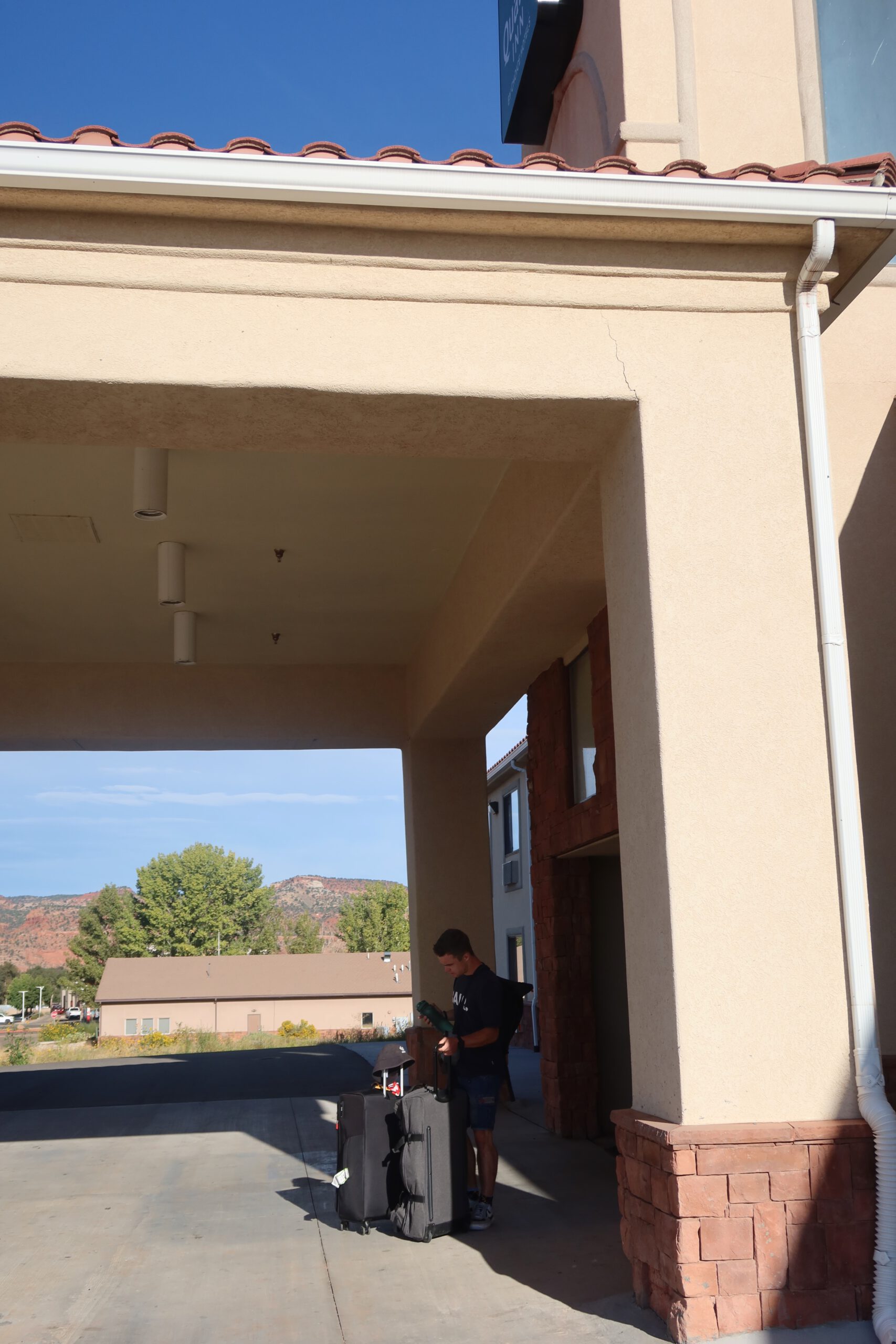 Guest unloading luggage at Quality Inn Kanab National Park Area with red rock mountains in the background in Kanab, Utah