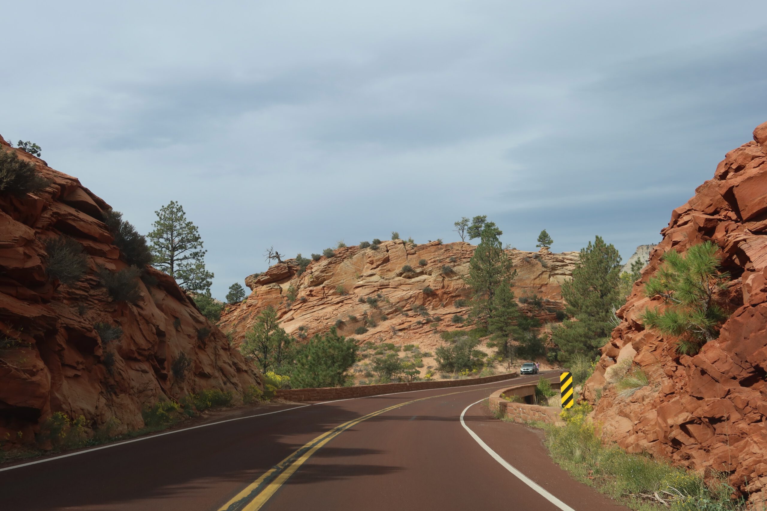 Winding road through narrow red rock canyon walls in Zion National Park, scenic drive surrounded by sandstone cliffs