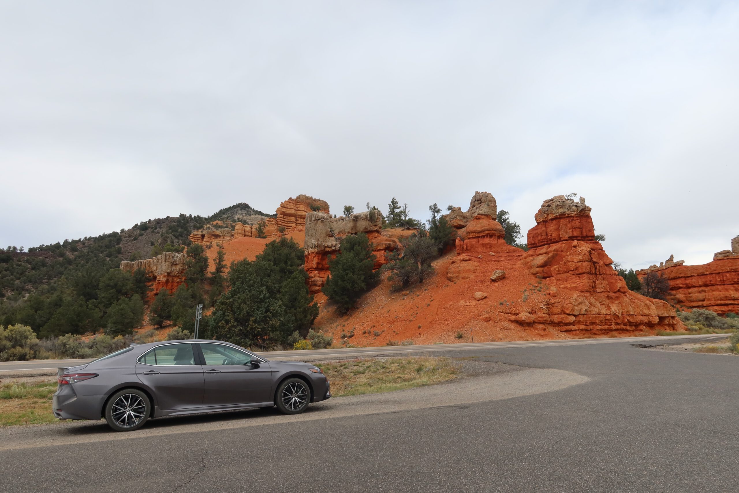 Parked car along Scenic Byway 12 with red rock formations in Dixie National Forest, Utah, capturing a classic road trip stop near Red Canyon