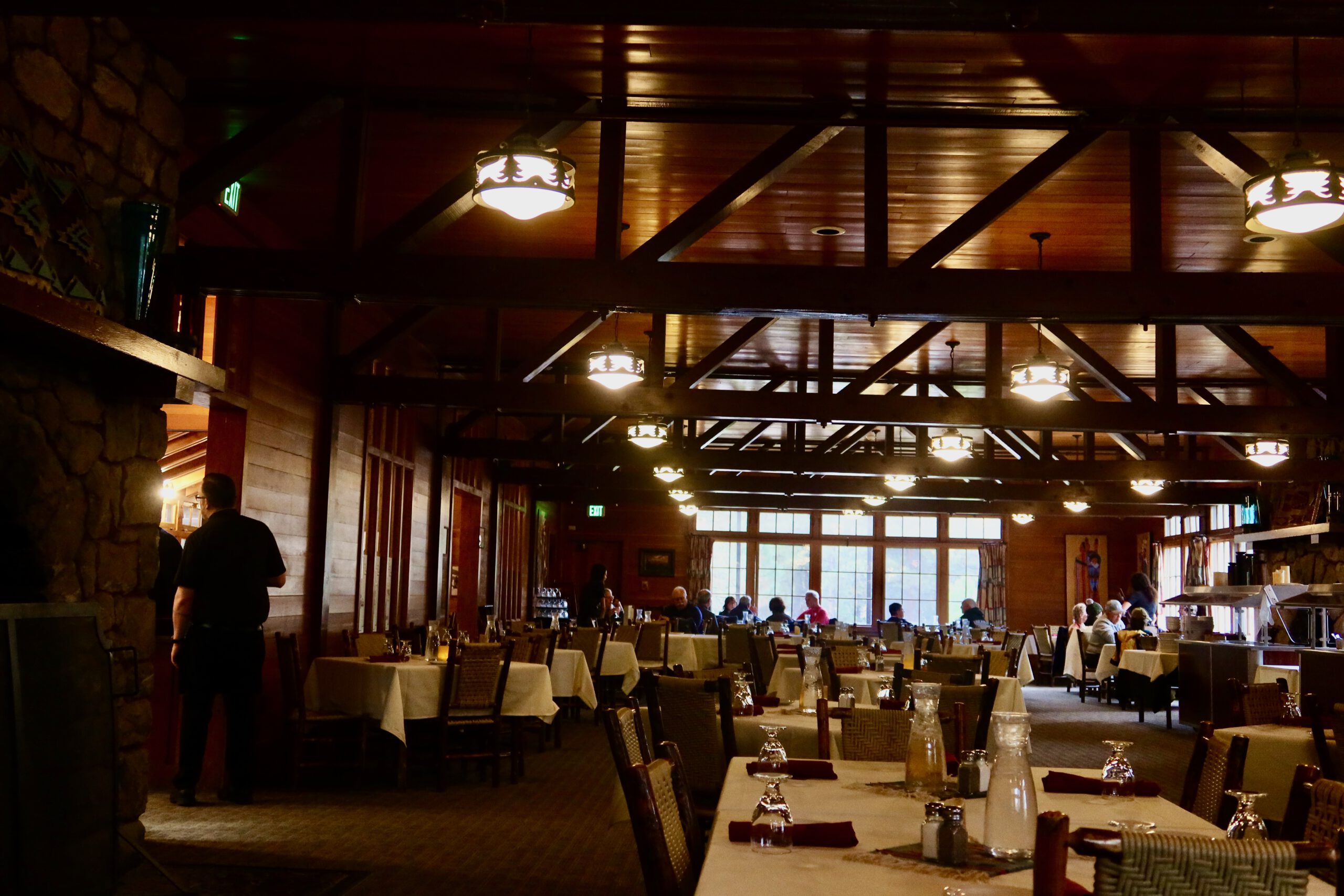 Interior of The Lodge at Bryce Canyon Restaurant with warm wooden beams, rustic lodge atmosphere, and guests dining inside Bryce Canyon National Park