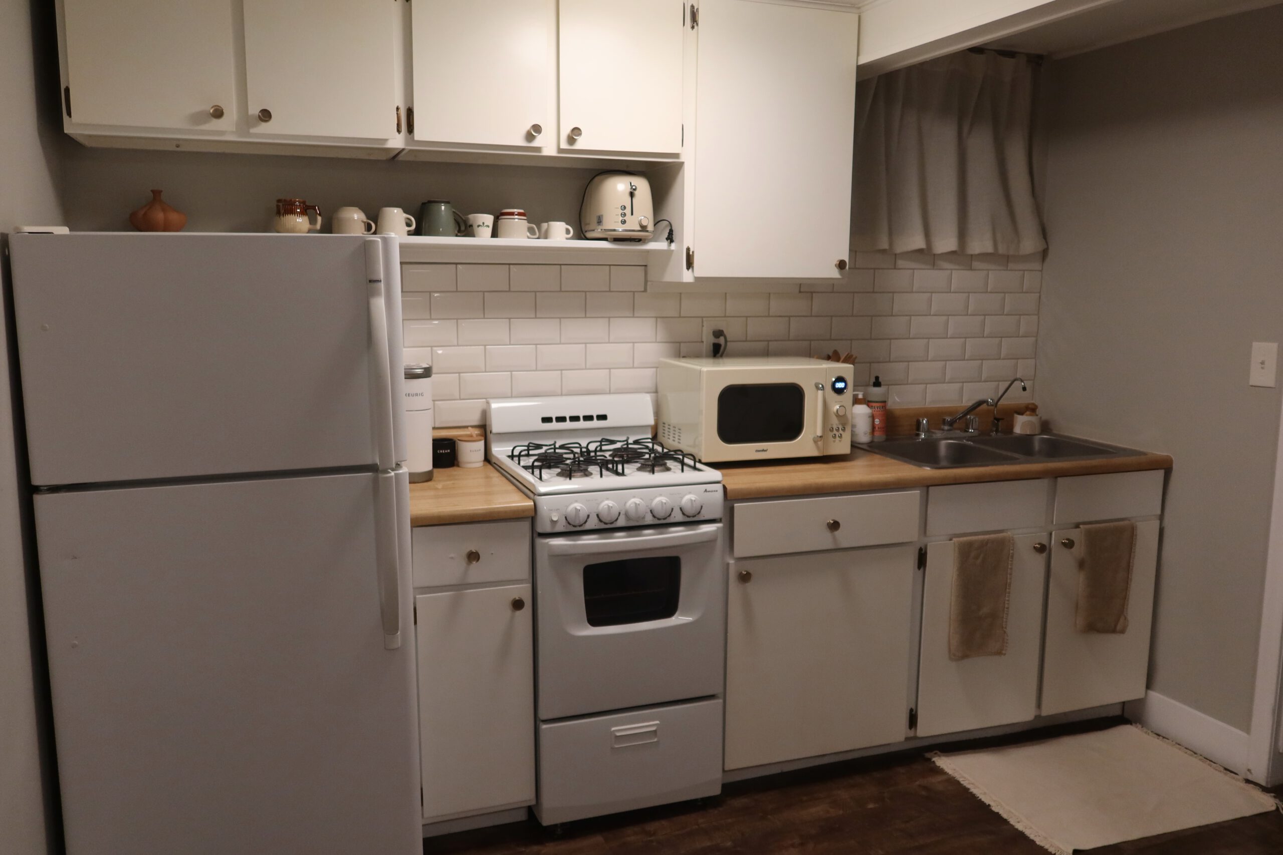 Fully equipped kitchen in a Sandy Utah Airbnb basement stay, featuring a gas stove, oven, microwave, refrigerator, double sink, and cooking essentials, ideal for a practical Utah road trip stop
