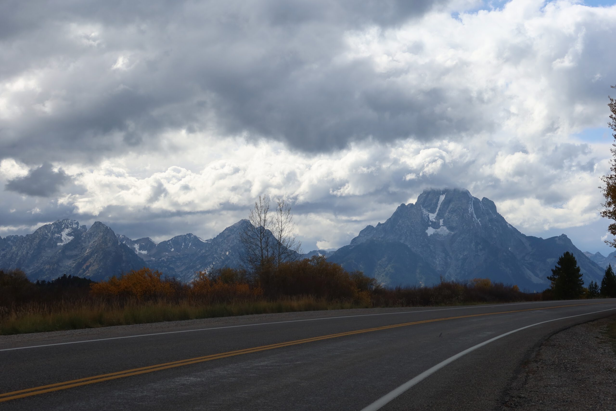 Scenic mountain road near Yellowstone National Park with dramatic clouds and rugged peaks, classic Wyoming road trip scenery