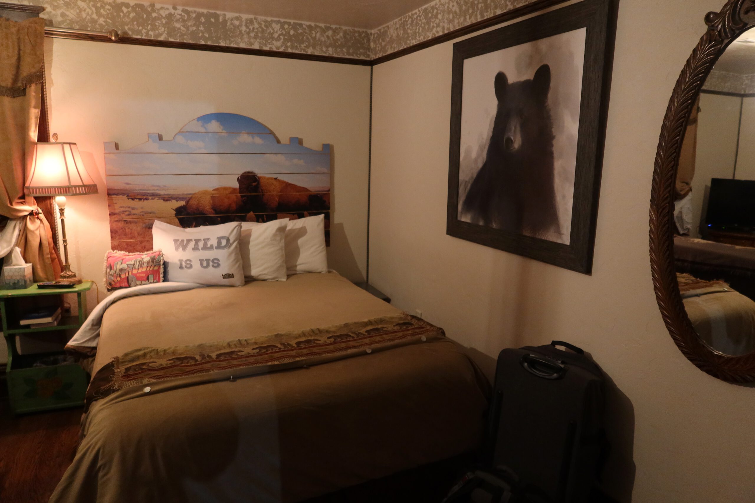 Queen bed bedroom in room 201 at Park Hotel Yellowstone, western themed hotel room with Yellowstone wildlife decor in Gardiner Montana