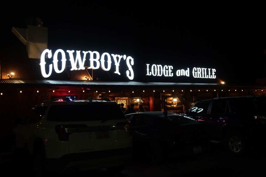 Cowboy Lodge and Grill restaurant in Gardiner Montana at night, illuminated western style signage near Yellowstone North Entrance