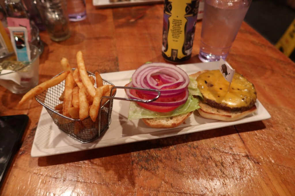 Plated cheeseburger and fries with craft beer on a wooden table at Cowboy’s Lodge and Grill in Gardiner, Montana.