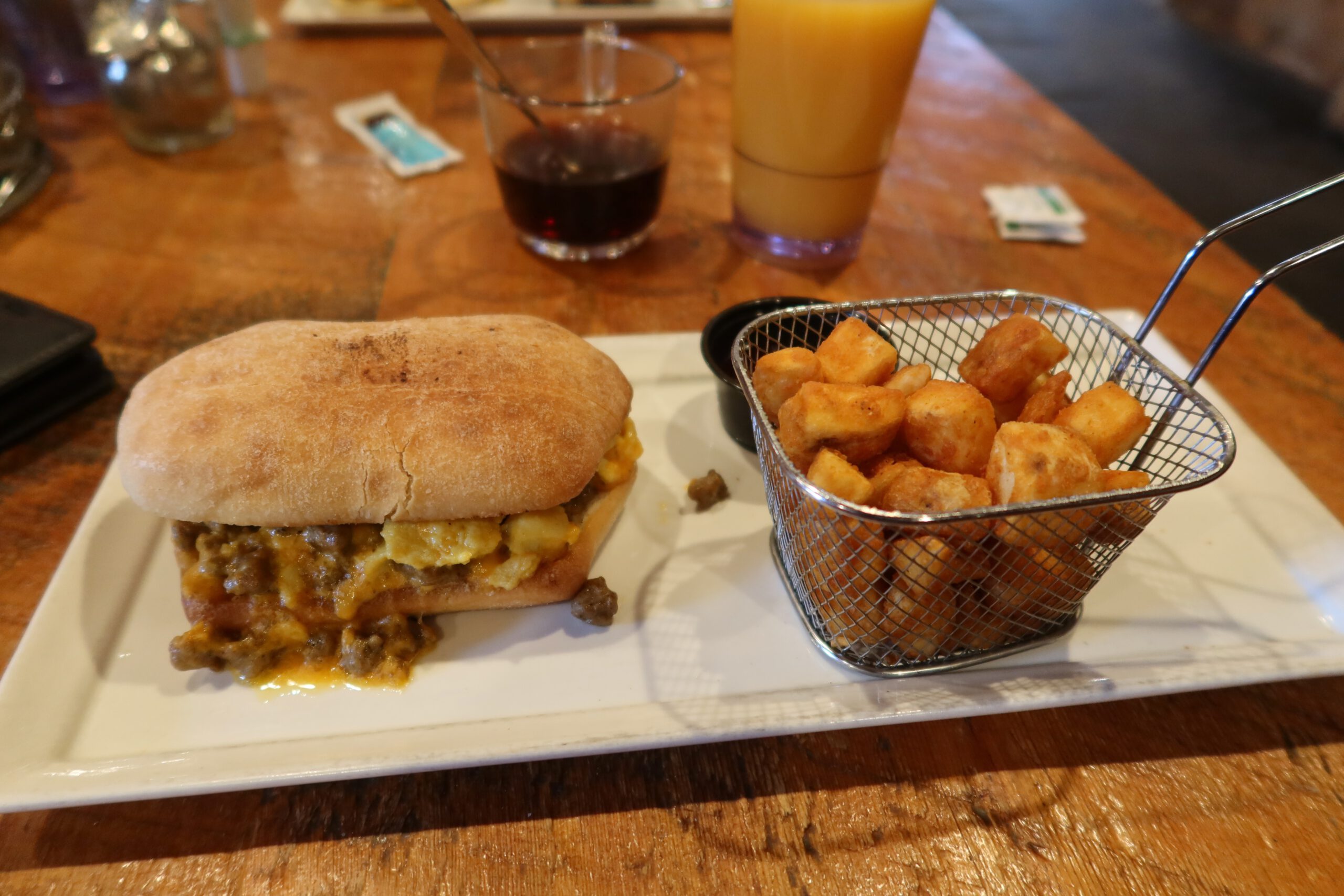 Hearty breakfast sandwich with scrambled eggs and savory gravy, served with crispy breakfast potatoes at Cowboy’s Lodge and Grille in Gardiner Montana. "Home On The Ranch" is served.