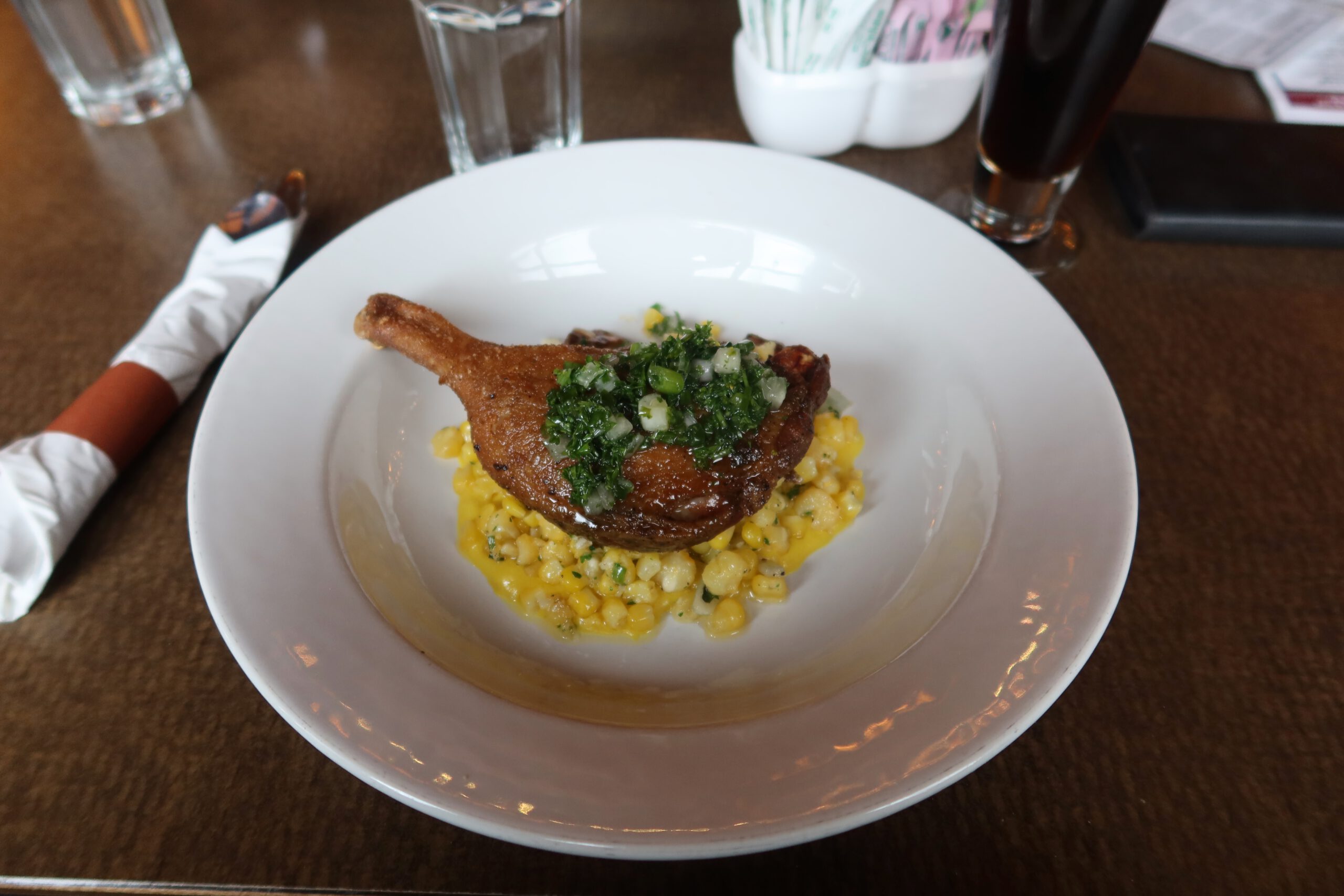 Seared duck leg served with creamy corn succotash and fresh herb salsa, a refined dinner dish enjoyed in Gardiner near Yellowstone National Park