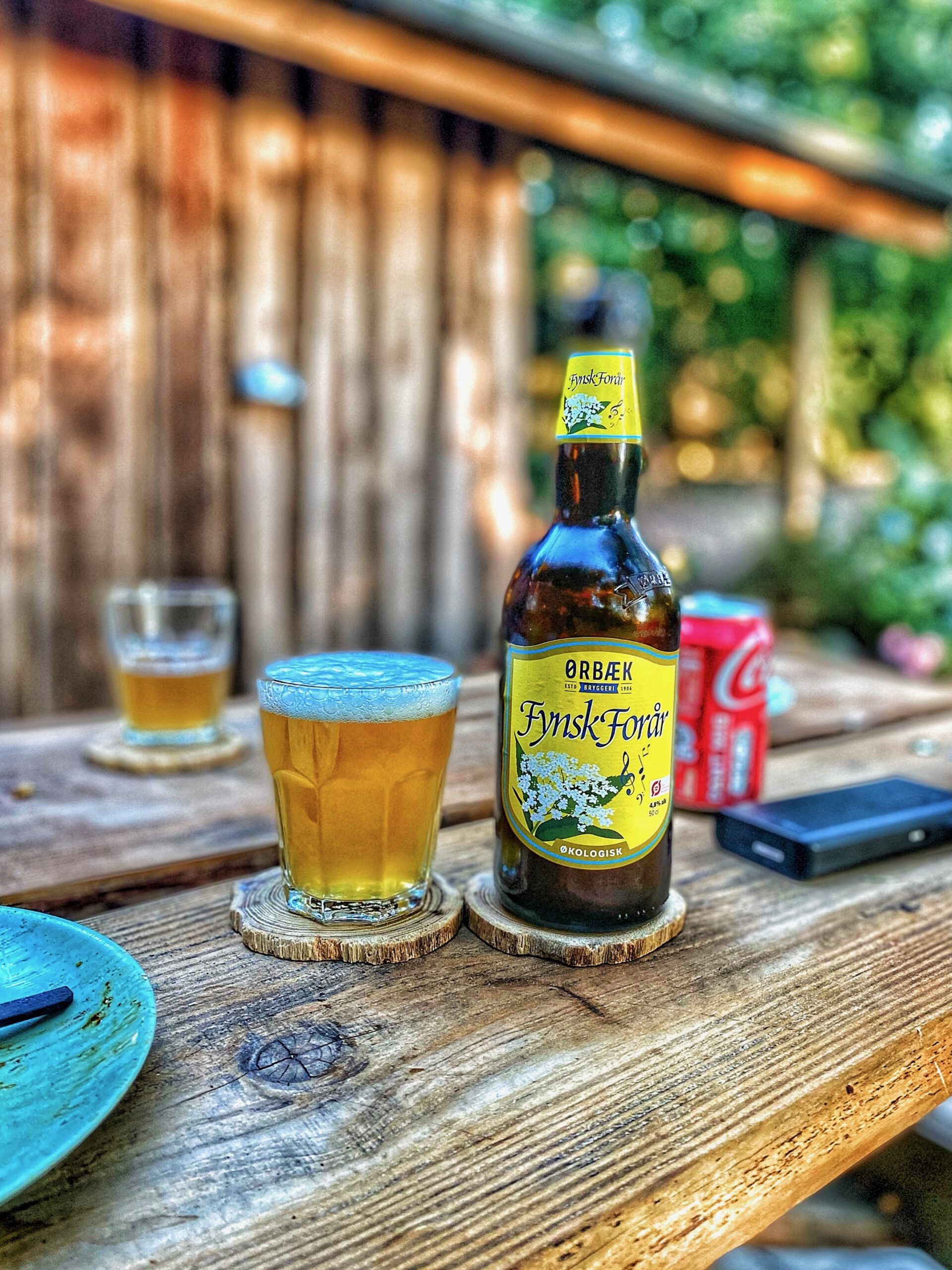 Solevad Cottage in the Forest, local Danish craft beer served outdoors on a wooden table surrounded by forest scenery
