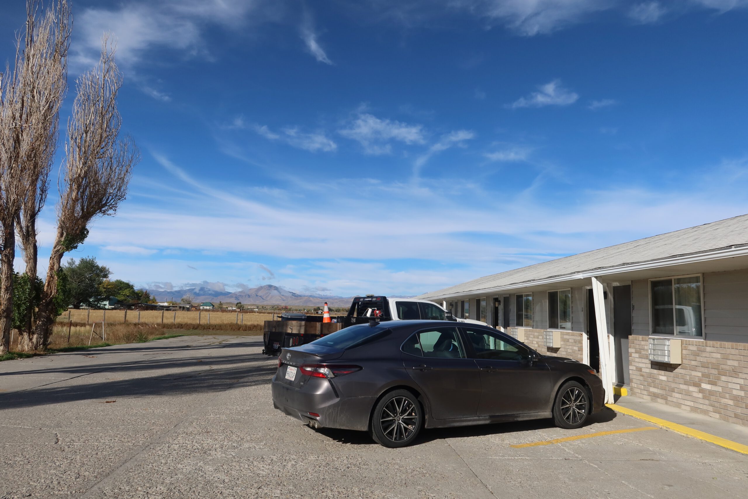 Free on site parking at Arco Inn Motel in Arco, Idaho, with a car parked directly in front of the motel room, highlighting easy access and classic American roadside motel convenience