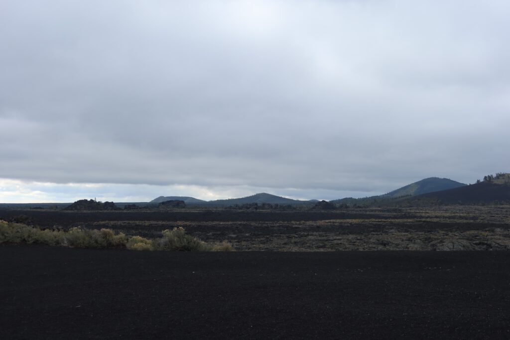 Wide view over expansive lava fields and volcanic cones at Craters of the Moon National Monument in Idaho under a cloudy sky