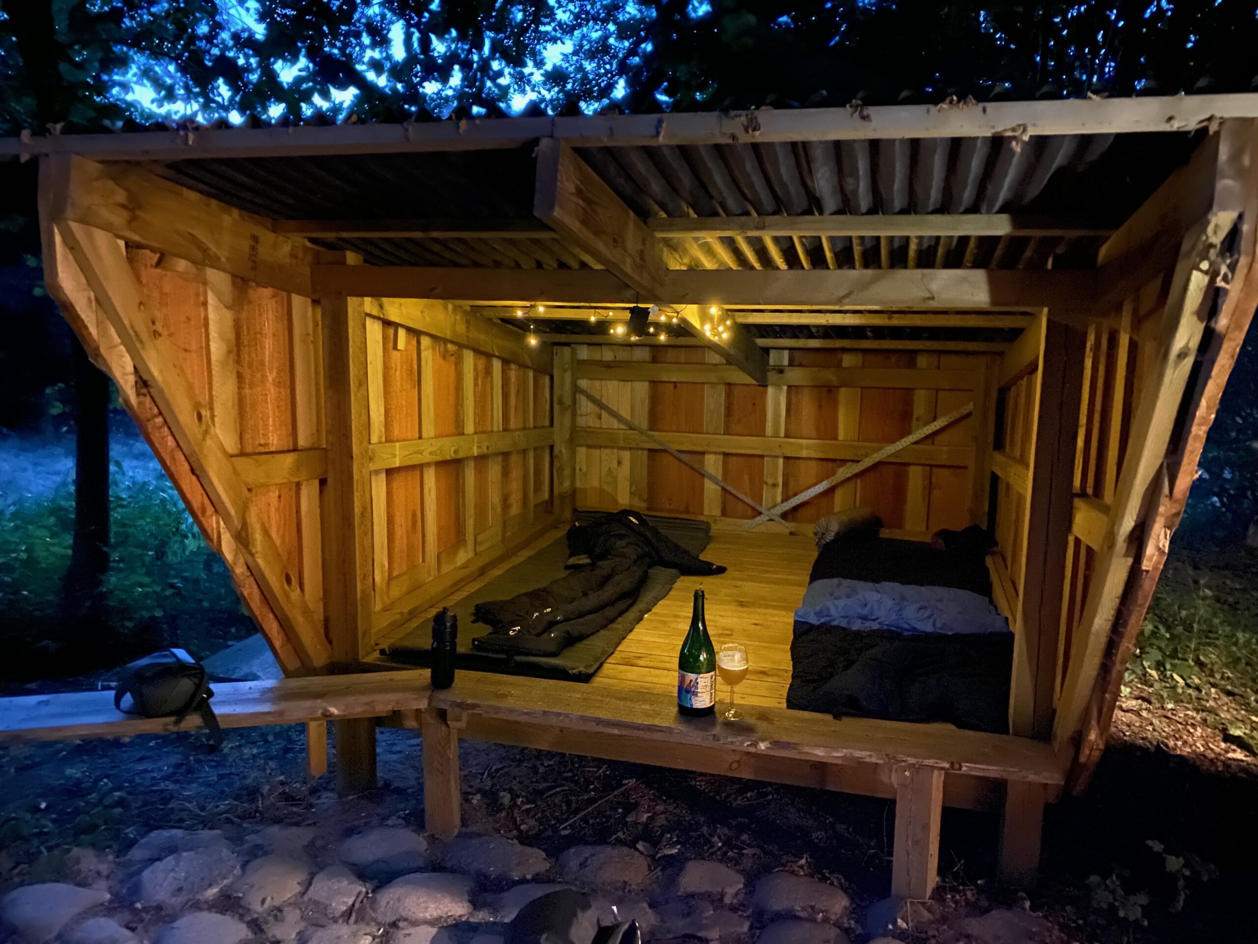 Solevad Cottage in the Forest, outdoor sleeping shelter with mattresses and warm lighting in a quiet forest setting